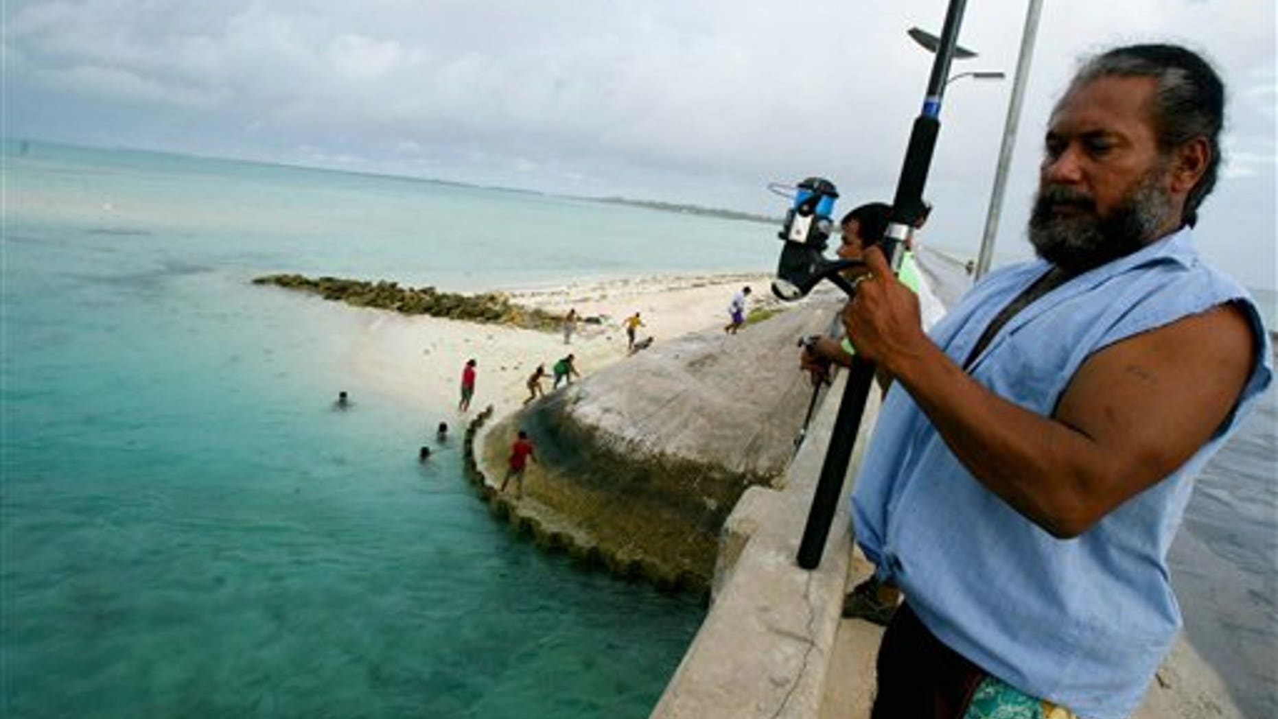 FILE - In this March 30, 2004 file photo, a man fishes on a bridge on Tarawa atoll, Kiribati.