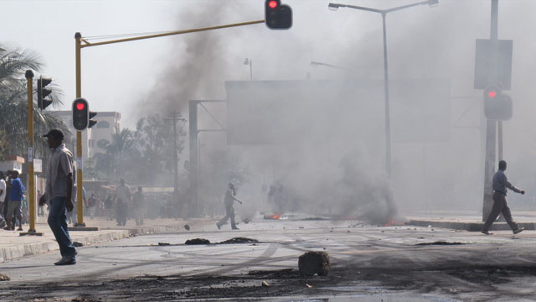 September 1: People walk past barricades of burning tires in Maputo, Mozambique after police opened fire on stone-throwing crowds who were protesting rising prices in this impoverished country. (AP)