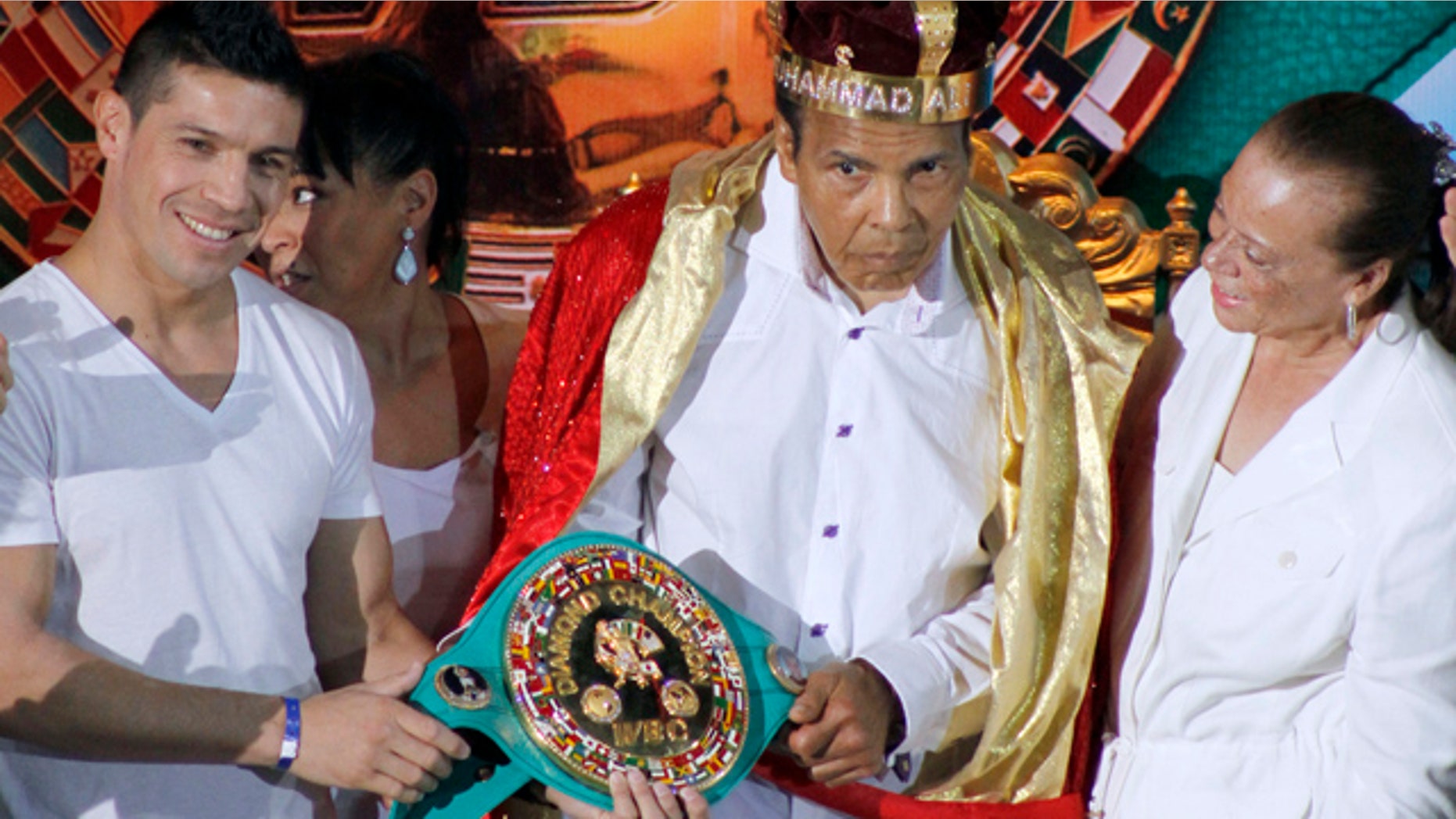 FILE - In this Monday, Dec. 3, 2012, file photo, the former heavyweight boxing champion Muhammad Ali, center, is crowned 'King of Boxing' while accompanied by his wife, Lonnie, right, and Argentine boxer Sergio Martinez during the 50th convention of the World Boxing Council in Cancun, Mexico. (AP Photo/Israel Leal, File)