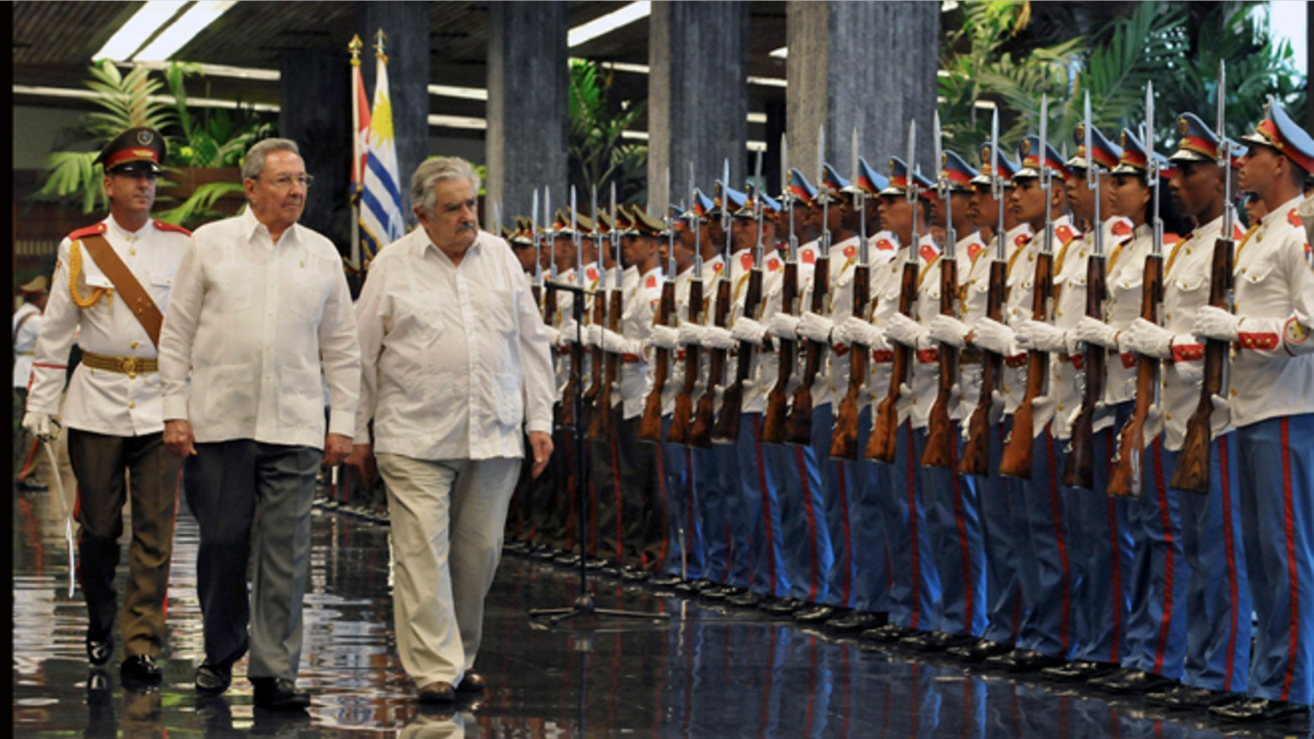 Cuba's President Raul Castro, left, and Uruguay's President Jose Mujica review the honor guard during a welcoming ceremony at Revolution Palace in Havana, Cuba, Wednesday, July 24, 2013. (AP Photo/Ernesto Mastrascusa, Pool)