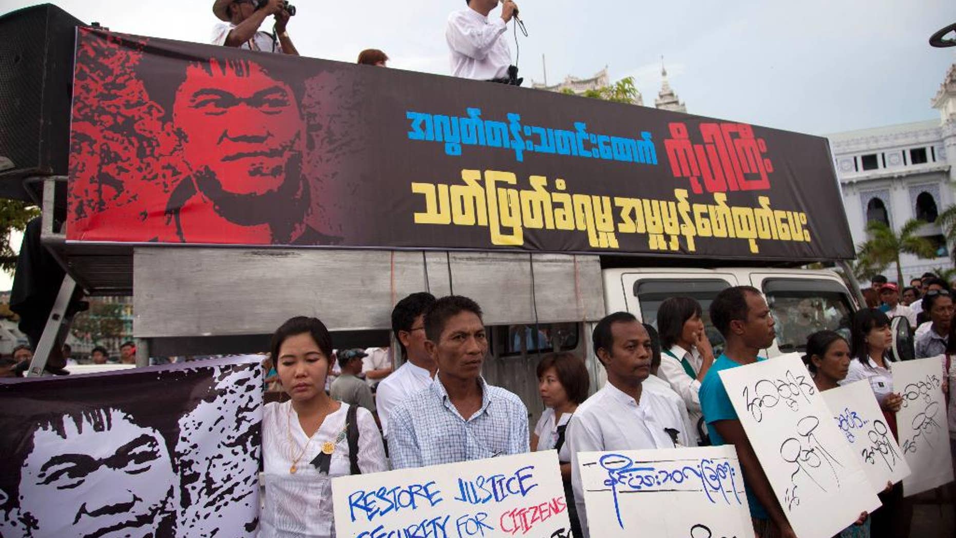 FILE - In this Oct. 26, 2014 file photo, Min Ko Naing, right on vehicle, a leader of Myanmar Prominent 88 Generation Students Group, speaks as activists hold placards during a protest against the killing of a freelance journalist, outside the city hall in Yangon, Myanmar. Myanmar's army on Oct. 4 shot dead Aung Kyaw Naing who was detained while covering clashes between the army and ethnic Karen rebels in Mon state in September. The body of the freelance journalist shot by Myanmar's army show signs that he was tortured before he died, the wife of the journalist said Thursday, Nov. 6, 2014. (AP Photo/Khin Maung Win, File)