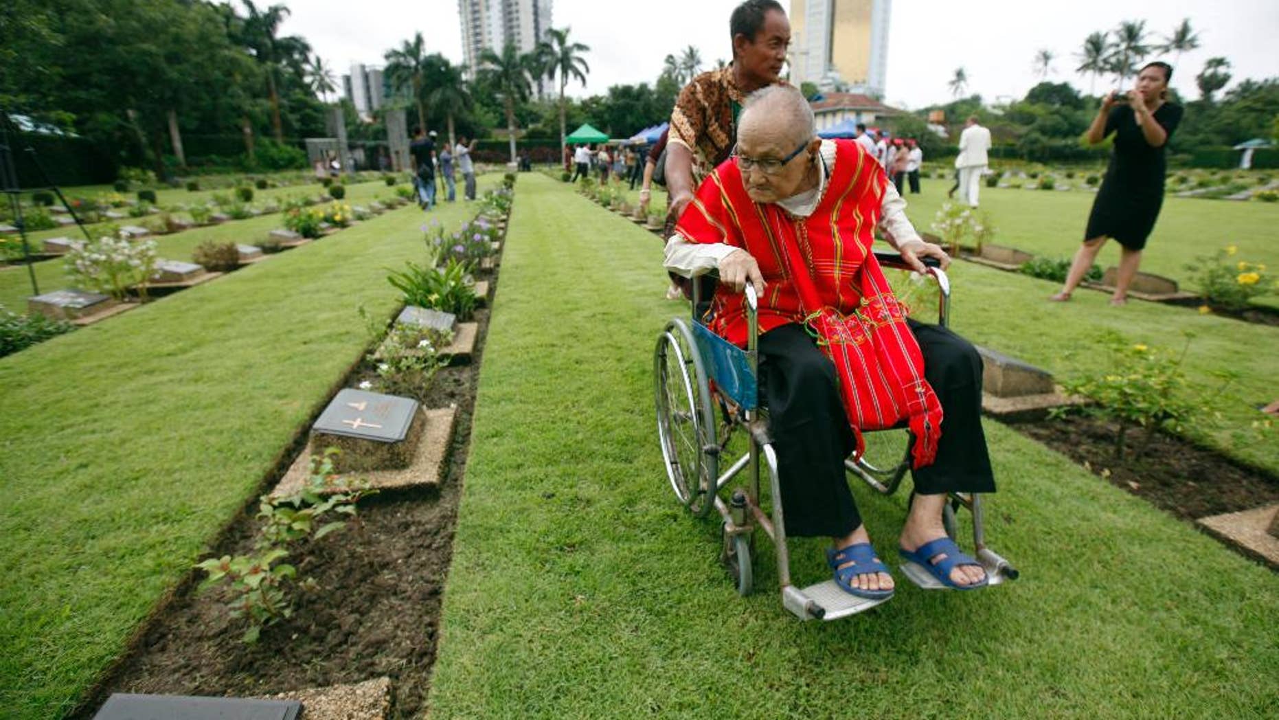 World War II veteran Saw Berny, who is ethnic Karen, looks at a gravestone as he attends a ceremony to mark the 70th anniversary of the end of World War II at Hanthawaddy War Cemetery in Yangon, Myanmar, Saturday, Aug. 15, 2015. Karen fought courageously behind Japanese lines with Seagrim, a lanky, eccentric and exceptional guerrilla leader. (AP Photo/Khin Maung Win)