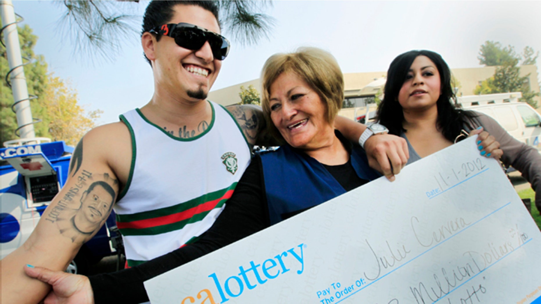 Nov. 2, 2012: Lottery winner Julie Cervera, center, looks at her recently dead son pictured on a tattoo, as she is hugged by her grandson Rudy Ray, left, and daughter Charliena Marquez, right, after a news conference in San Bernardino, Calif.