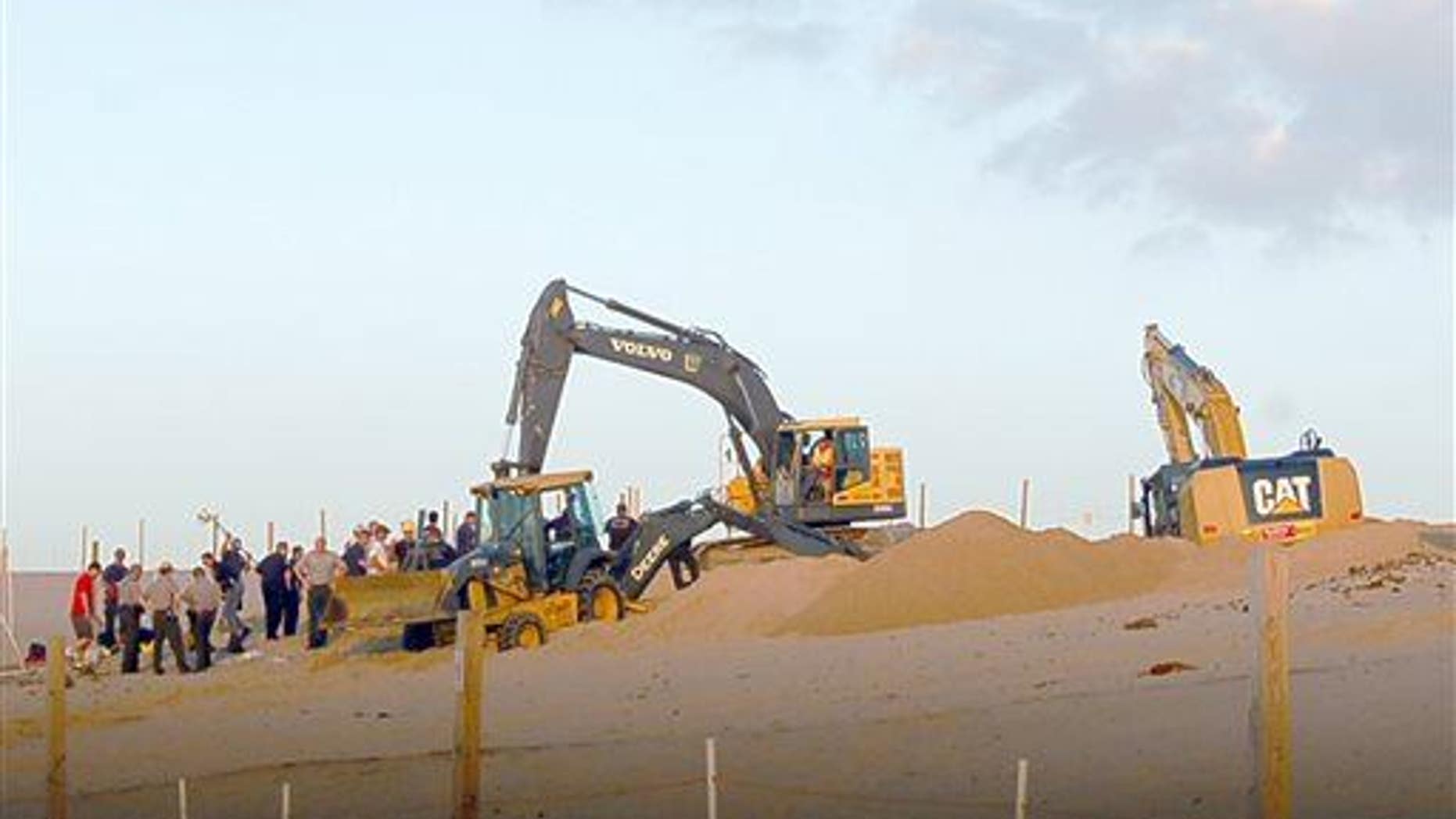 In this July 12, 2013, photo rescue workers with heavy equipment working to free 6-year-old Nathan Woessner who fell into a hole in a massive sand dune at the Indiana Dunes National Lakeshore.
