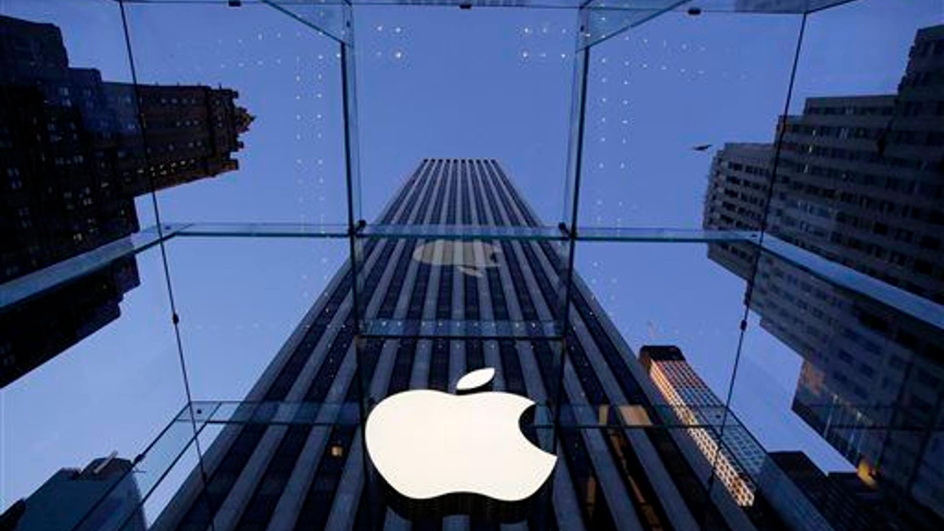 In this Sept. 5, 2014 file photo, the Apple logo hangs in the glass box entrance to the company's Fifth Avenue store, in New York.
