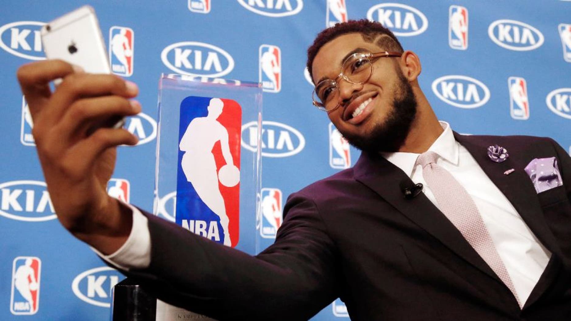 Minnesota Timberwolves' Karl-Anthony Towns takes a selfie with his NBA Rookie of the Year trophy next to him after a news conference announcing his selection.