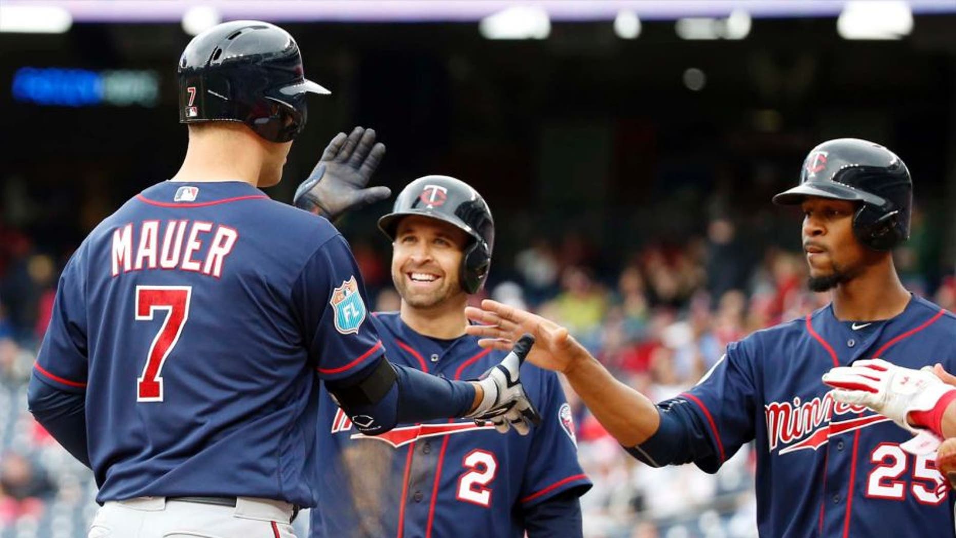 Saturday, April 2: The Minnesota Twins' Joe Mauer (left) celebrates knocking in Brian Dozier (center) and Byron Buxton with a three-run home run during the third inning of an exhibition baseball game against the Washington Nationals at Nationals Park in Washington.