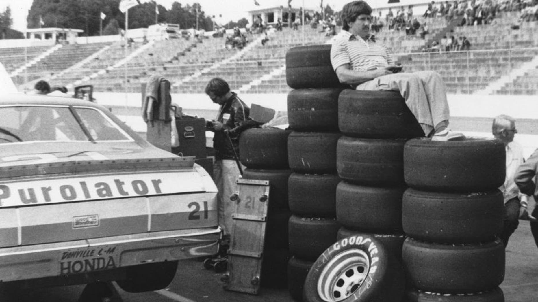 MARTINSVILLE, VA 1980: Driver Neil Bonnett uses a stack of Goodyear tires as a makeshift easy chair as he watches practice for a NASCAR Cup race at Martinsville Speedway. (Photo by ISC Images & Archives via Getty Images)