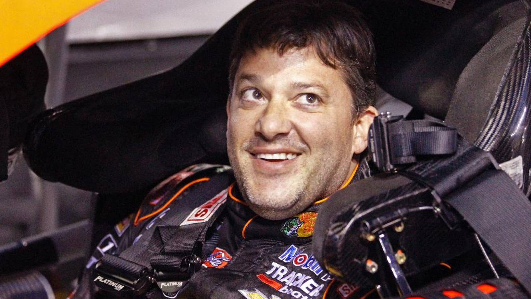 Tony Stewart smiles as he sits in his car before qualifying for Saturday's NASCAR Bank of America Sprint Cup series auto race at Charlotte Motor Speedway in Concord, N.C., Thursday, Oct. 9, 2014. (AP Photo/Terry Renna)