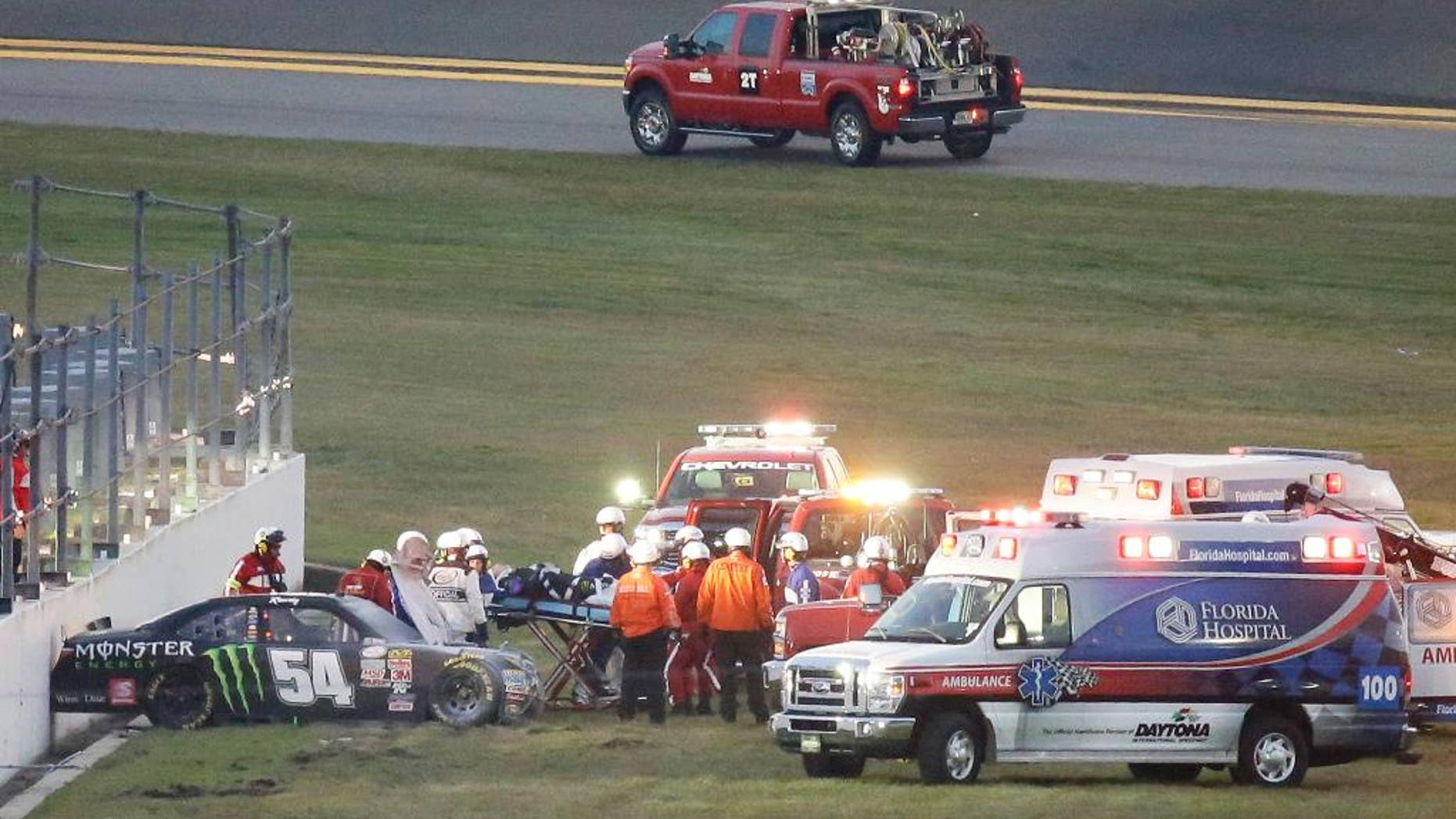 FILE - In this Feb. 21, 2015, file photo, Kyle Busch, center, is taken to an ambulance on a stretcher after he was involved in a multi-car crash during the Xfinity series auto race at Daytona International Speedway in Daytona Beach, Fla. He knew it was going to be bad when his car slid through the grass into the wall, and he knew immediately that both his leg and foot were broken. (AP Photo/John Raoux, File)