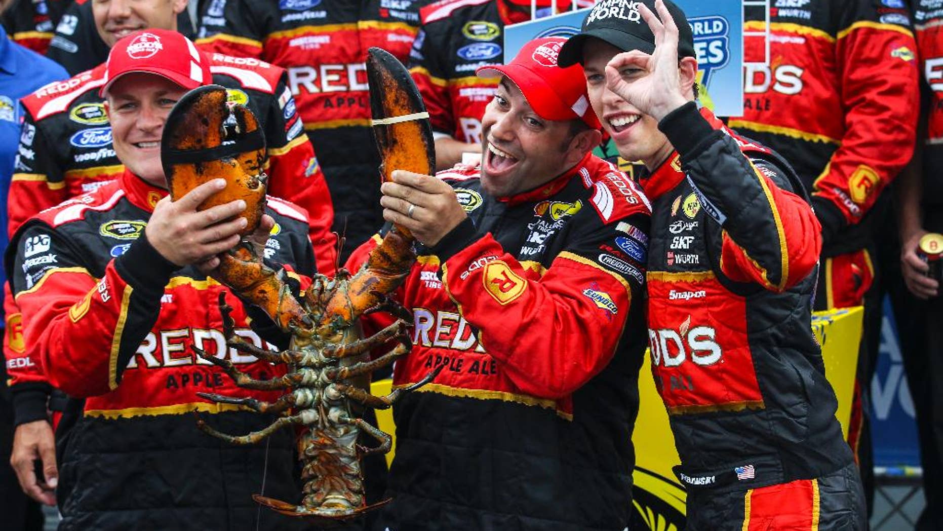 Brad Keselowski, right, gestures while celebrating with members of his team, holding a lobster, in Victory Lane after winning the NASCAR Sprint Cup series auto race at New Hampshire Motor Speedway on Sunday, July 13, 2014, in Loudon, N.H. (AP Photo/Cheryl Senter)