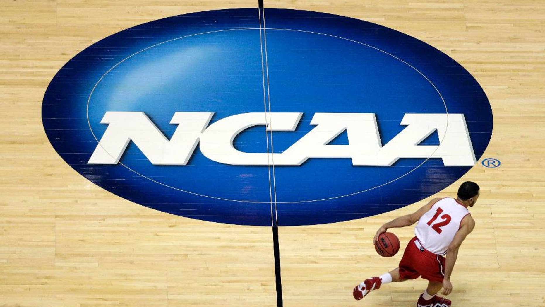 FILE - In this March 26, 2014, file photo, Wisconsin's Traevon Jackson dribbles past the NCAA logo during practice at the NCAA men's college basketball tournament in Anaheim, Calif. A federal judge ruled that the NCAA can't stop players from selling the rights to their names, images and likenesses, striking down NCAA regulations that prohibit them from getting anything other than scholarships and the cost of attendance at schools. U.S. District Judge Claudia Wilken in Oakland, Calif., ruled in favor Friday, Aug. 8, of former UCLA basketball star Ed O'Bannon and 19 others in a lawsuit that challenged the NCAA's regulation of college athletics on antitrust grounds. (AP Photo/Jae C. Hong, File)