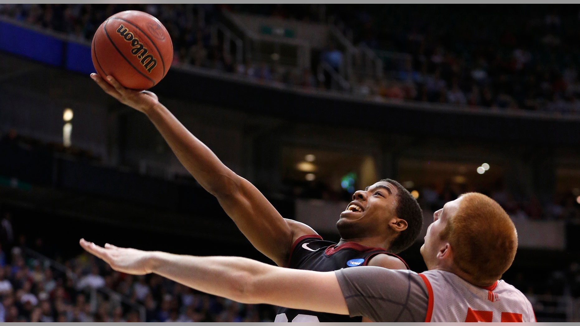 Harvard guard Wesley Saunders (23) takes a shot while defended by New Mexico center Alex Kirk (53) during the second half of their second round NCAA tournament basketball game in Salt Lake City, Utah.