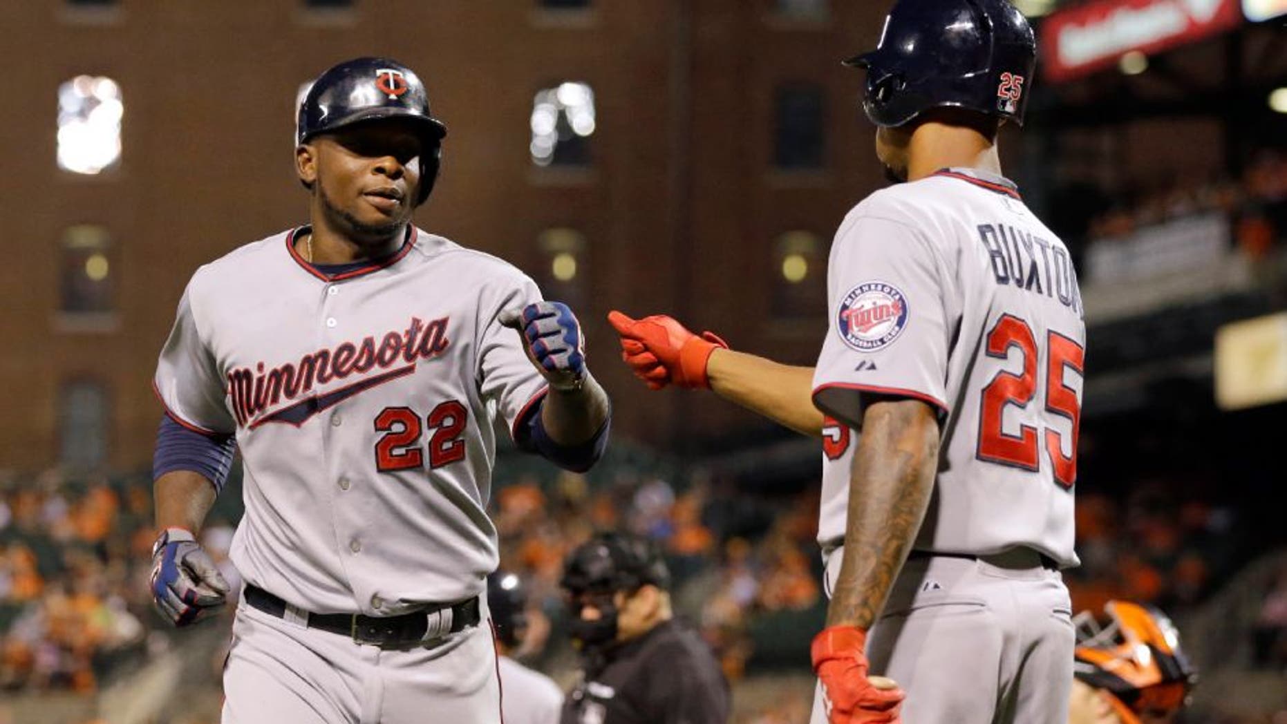 Minnesota Twins' Miguel Sano, left, fist-bumps teammate Byron Buxton after scoring on a bases-loaded walk to Eduardo Nunez during the fourth inning of a baseball game against the Baltimore Orioles, Friday, Aug. 21, 2015, in Baltimore. (AP Photo/Patrick Semansky)