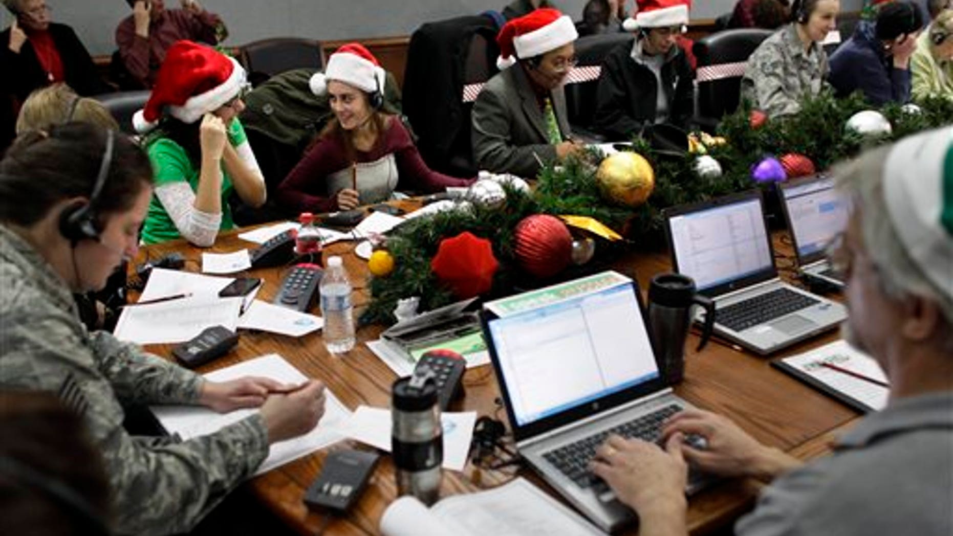 FILE - In this Dec. 24, 2012 file photo, Lizzie Solano, center, and her sister Sarah take phone calls from children asking where Santa is and when he will deliver presents to their house, during the annual NORAD Tracks Santa Operation, at the North American Aerospace Defense Command, or NORAD, at Peterson Air Force Base, in Colorado Springs, Colo. The U.S. and Canadian military will entertain millions of kids again this Christmas Eve with second-by-second updates on Santas global whereabouts. (AP Photo/Brennan Linsley, File)