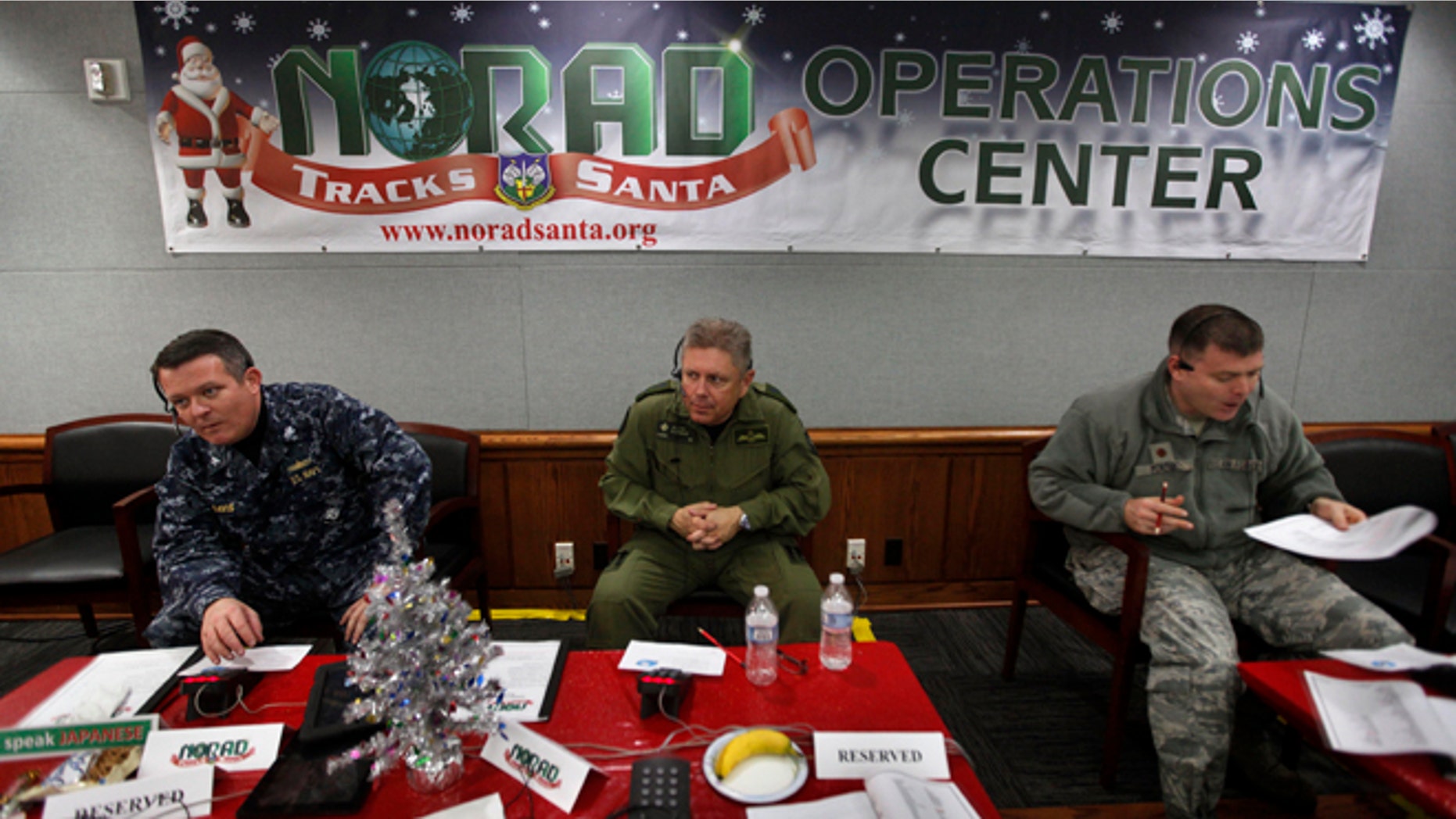 FILE 2012: NORAD Deputy Commander Lt. General Alain Parent, center, of the Royal Canadian Air Force, takes phone calls from children asking where Santa is and when he will deliver presents to their house, during the annual NORAD Tracks Santa Operation, at the North American Aerospace Defense Command, or NORAD, at Peterson Air Force Base, in Colorado Springs, Colo.