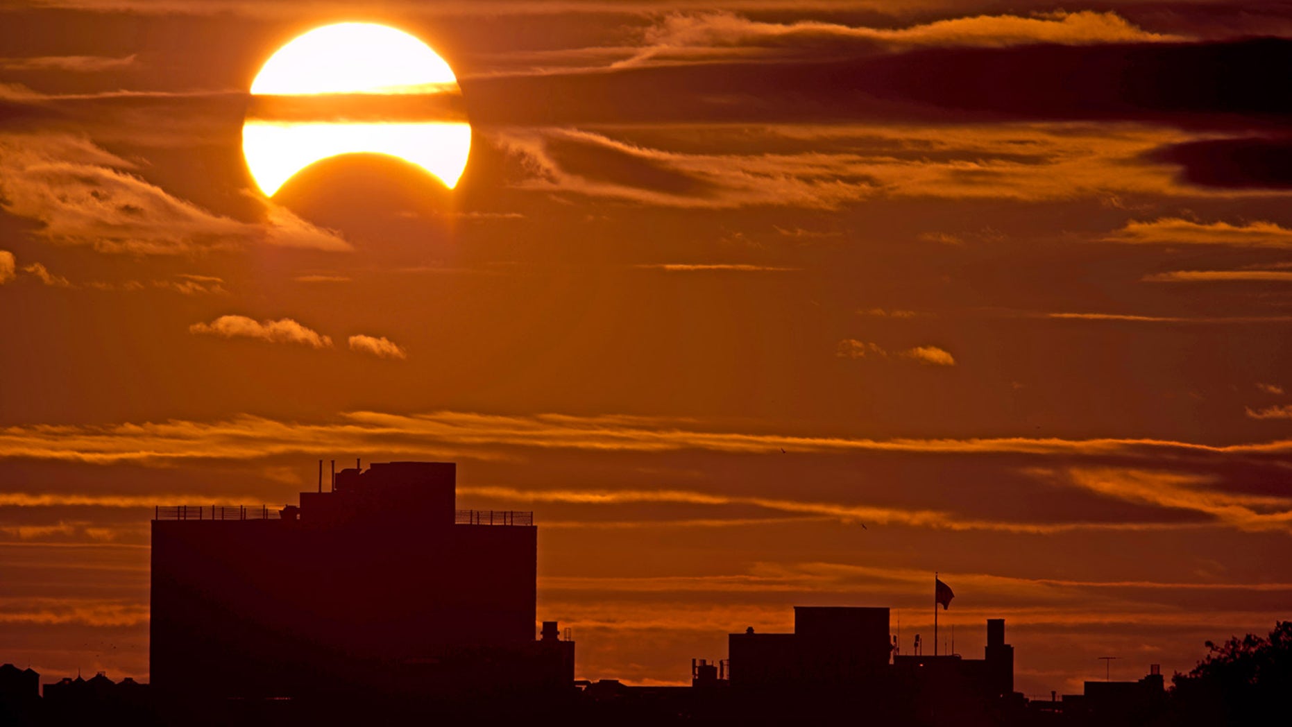 A partial solar eclipse is seen just after sunrise over the Queens borough of New York across the East River on Nov. 3, 2013.