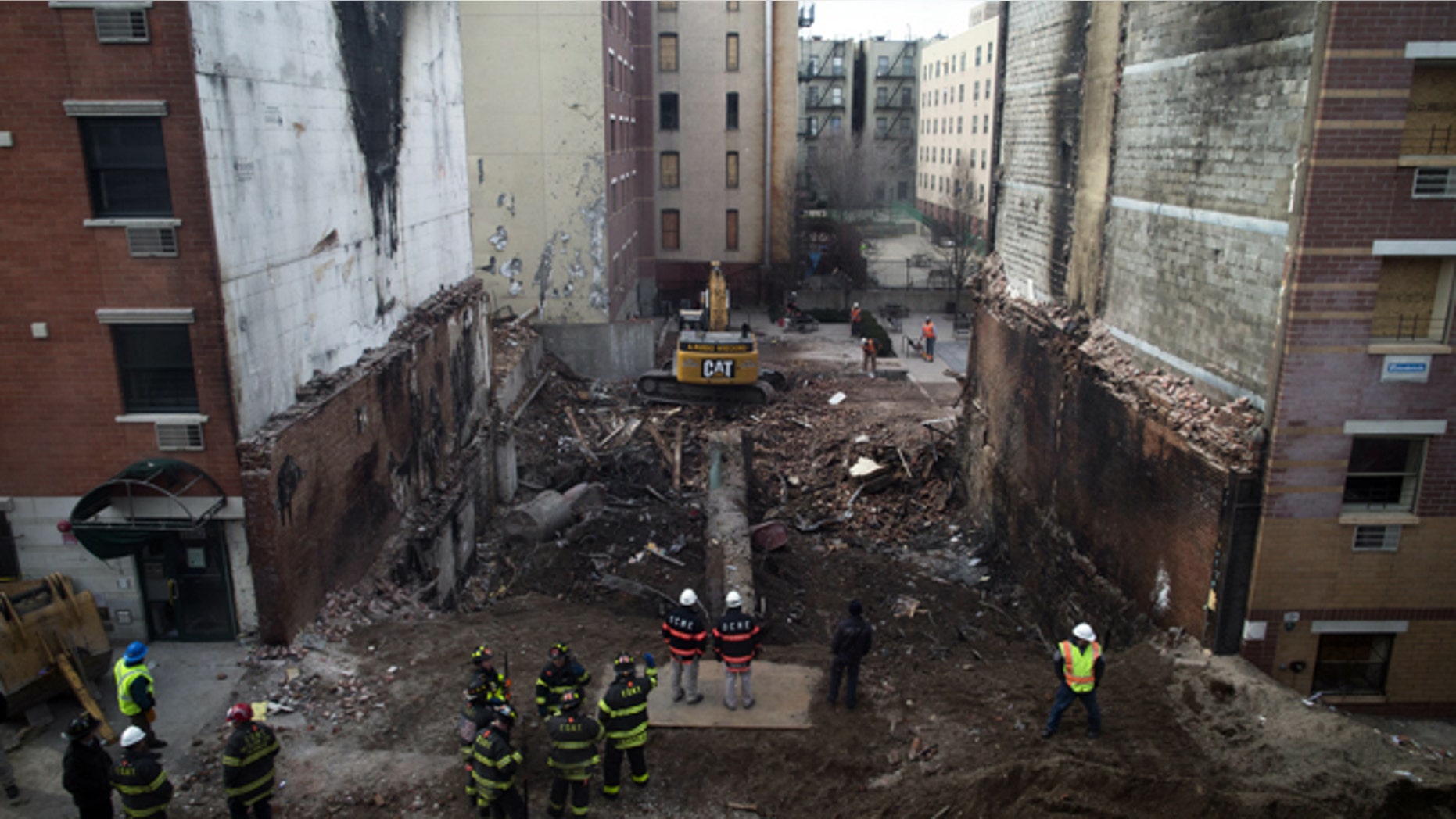 Workers stand beside the recently cleared basement of the two buildings leveled by an explosion on Wednesday in the East Harlem neighborhood of New York, Sunday, March 16, 2014. A pair of congregations gathered to mourn Sunday, one for its lost church and one for two members who lost their lives in the massive explosion. (AP Photo/John Minchillo)