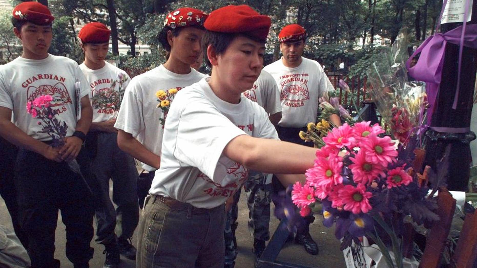 FILE - In this June 11, 1996 file photo, Guardian Angels from Tokyo place flowers at the site of a sexual assault of a woman the previous week in New York's Central Park. The Angels were in New York to meet with their New York counterparts. Guardian Angels volunteers recently made a pointed return to Central Park for the first time in over two decades. The anti-crime group says it felt compelled to resume nightly safety rounds in the iconic park because of a 28-percent rise in crime there so far this year. (AP Photo/Mark Lennihan, File)