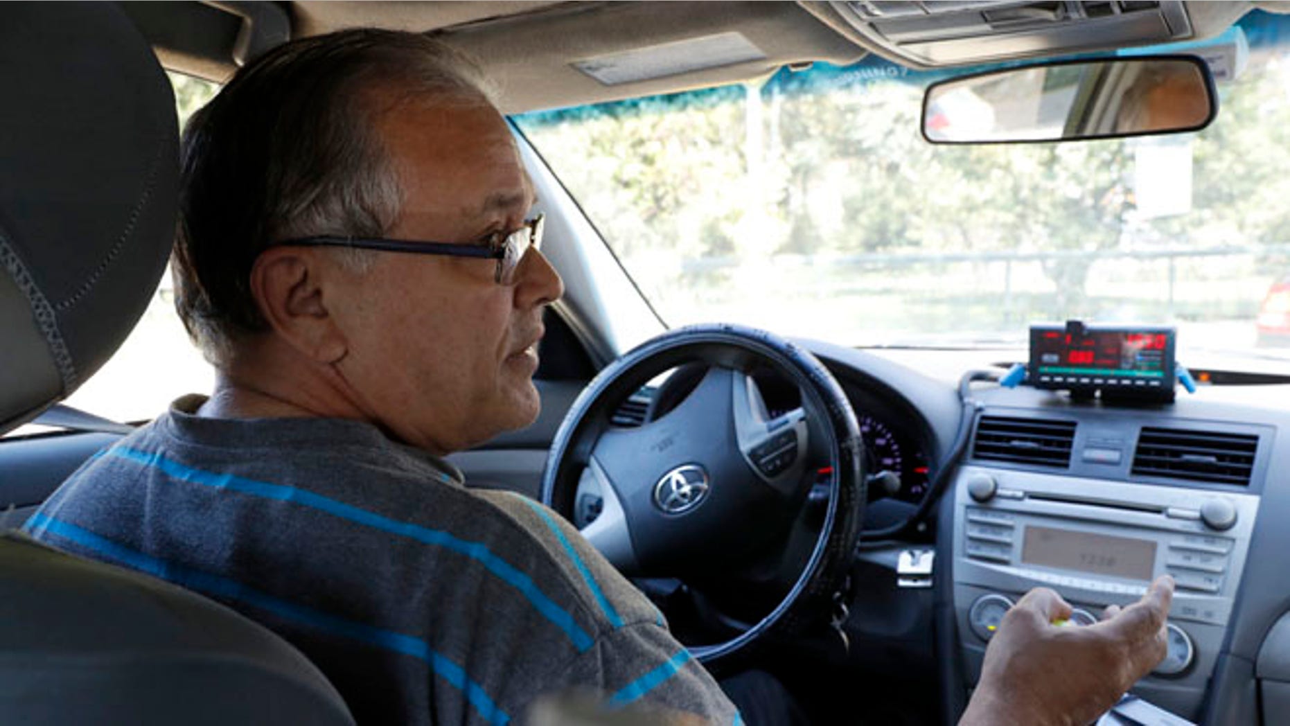 In this Wednesday, Aug. 24, 2016 photo, taxi driver Luis Rosado speaks to an Associated Press reporter while stopped at a red light in New York. Nearly 96 percent of cabbies are immigrants, and the city has dropped a longstanding requirement that they be required to speak and understand basic English. While immigrant advocates say the change makes it easier for newcomers to get work behind the wheel, some customers say it could make riding in a cab even more of an adventure. (AP Photo/Mary Altaffer)