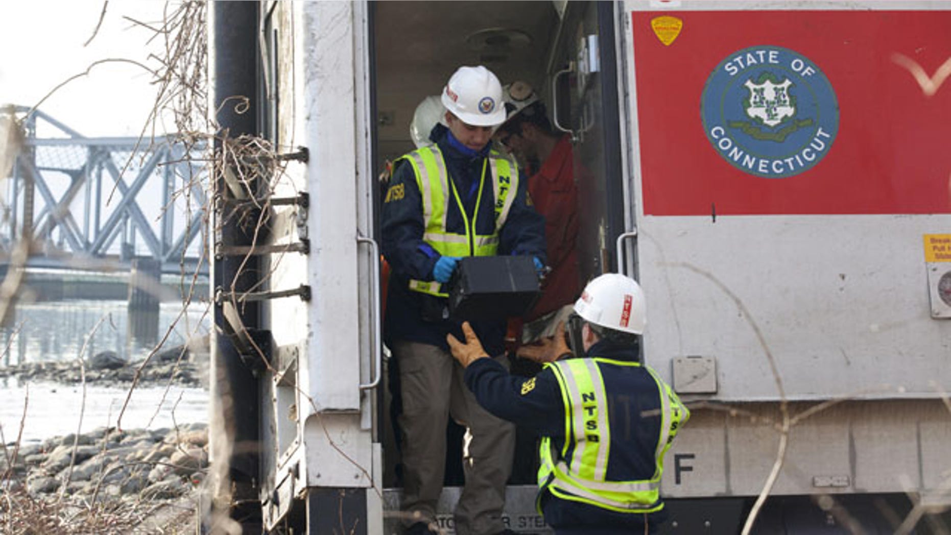 December 1, 2013: NTSB investigator George Haralampopoulous hands a data recorder down to Mike Hiller from the derailed Metro-North train in the Bronx borough of New York. (AP Photo/NTSB)