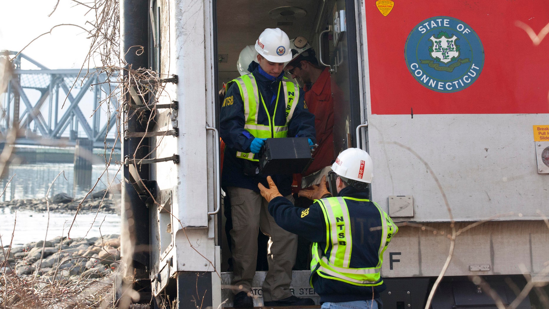 NTSB investigator George Haralampopoulous hands a data recorder down to Mike Hiller from the derailed Metro-North train in the Bronx borough of New York, on Dec 1, 2013.