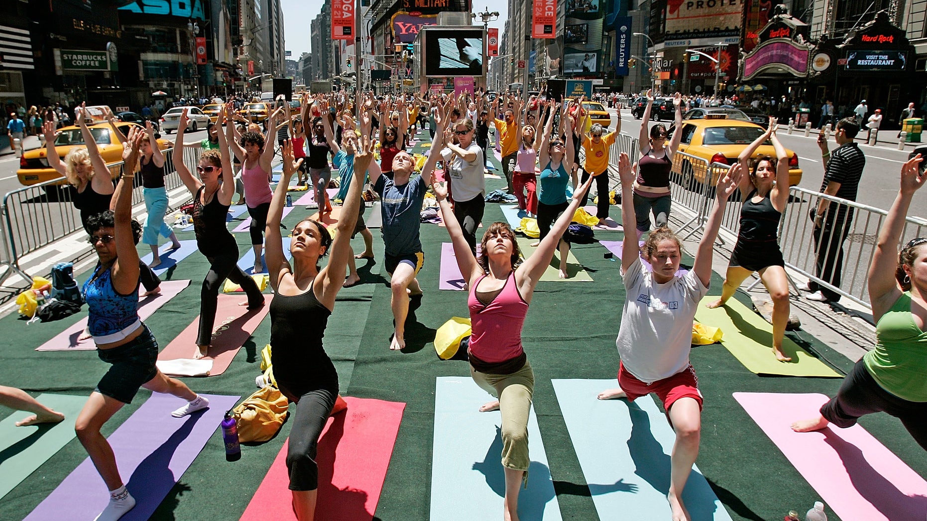Yoga enthusiasts from across the country unite in Times Square as taxis drive past in New York City.