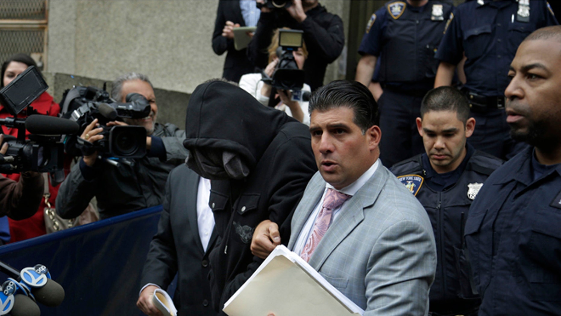 Wojciech Braszczok, center left, with face covered, leaves the courthouse in New York, Wednesday, Oct. 9, 2013. Braszczok, an undercover police detective, was charged with gang assault in a motorcycle rally that descended into violence in New York. (AP Photo/Seth Wenig)