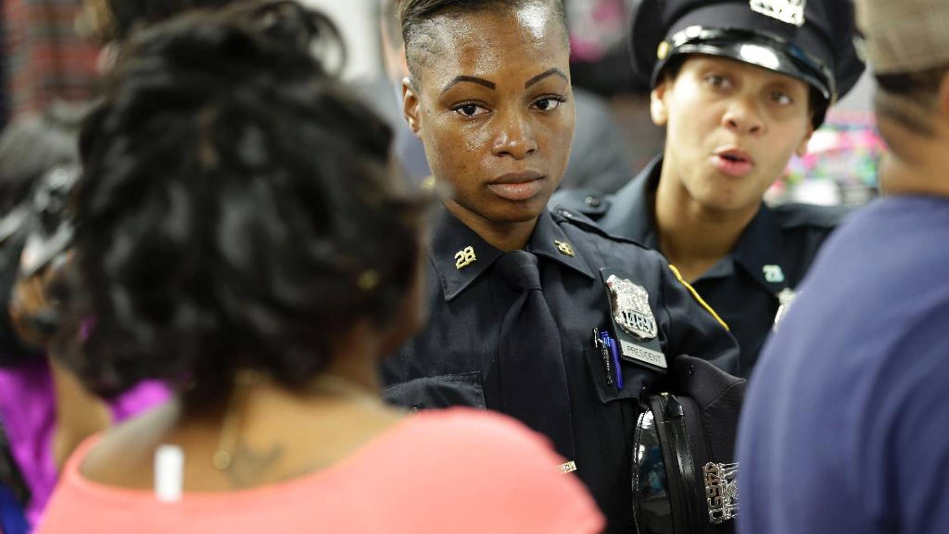 Police officers Shakara President, center, and Lanora Moore talk with an unhappy customer inside a store on 125th Street in the Harlem section of New York, Wednesday, April 29, 2015. (AP Photo/Seth Wenig)