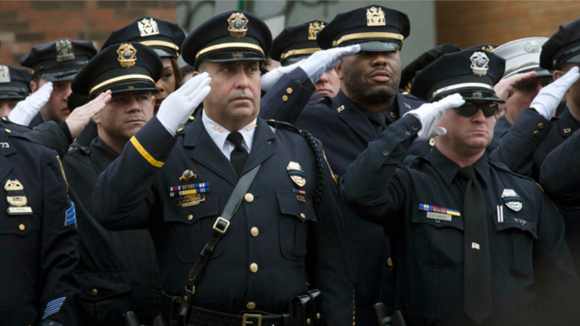 Jan. 4, 2015: Police officers salute along the procession route during the funeral of New York Police Department Officer Wenjian Liu, in the Brooklyn borough of New York. (AP Photo/John Minchillo)