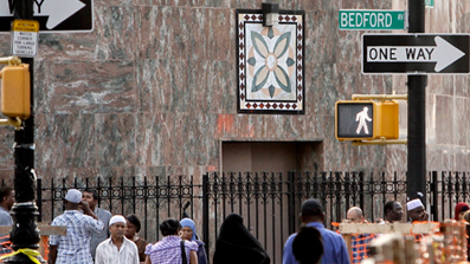 In this Aug. 18, 2011 photo, people pass below a New York Police Department security camera, upper left, which is above a mosque on Fulton St., in the Brooklyn neighborhood of Bedford-Stuyvesant in New York.