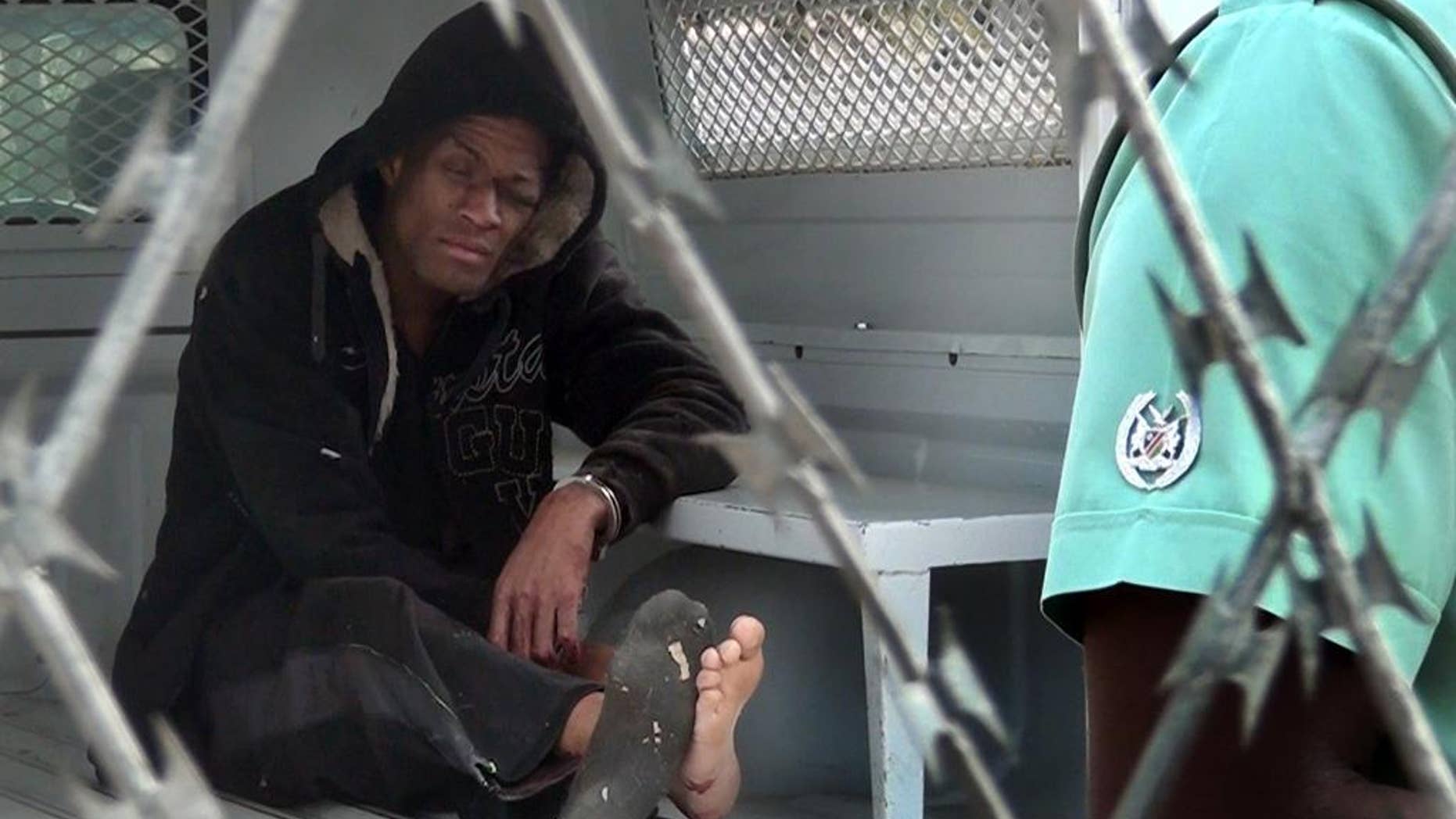American citizen Marcus Kevin Tomas, sits inside a police van in Windhoek, Namibia, Monday, Nov. 3, 2014. Tomas, on Sunday climbed a tree inside the Windhoek Central Prison and tried to jump over the barbed wire fence but instead landed on top of the fence. Prison authorities told the press agency that they found Tomas hanging from the barbed fence and called emergency medical services to remove him. (AP Photo/George Hendriks)