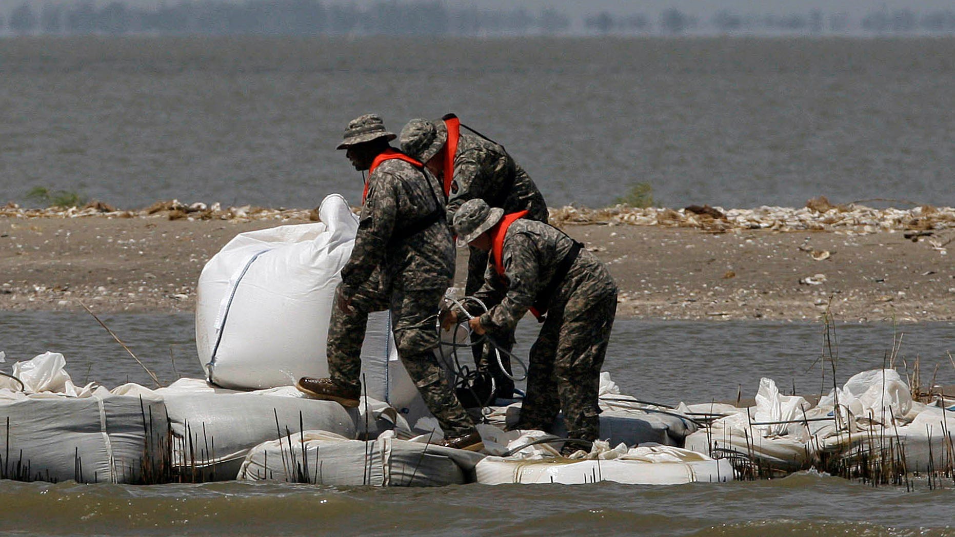 National Guardsmen walk along a barrier created by the National Guard from 2,000 pound bags of sand to block a pass in a effort to protect Scofield bay from oil from the Deepwater Horizon spill, Friday, June 11, 2010, near Venice, La.. (AP Photo/Eric Gay)
