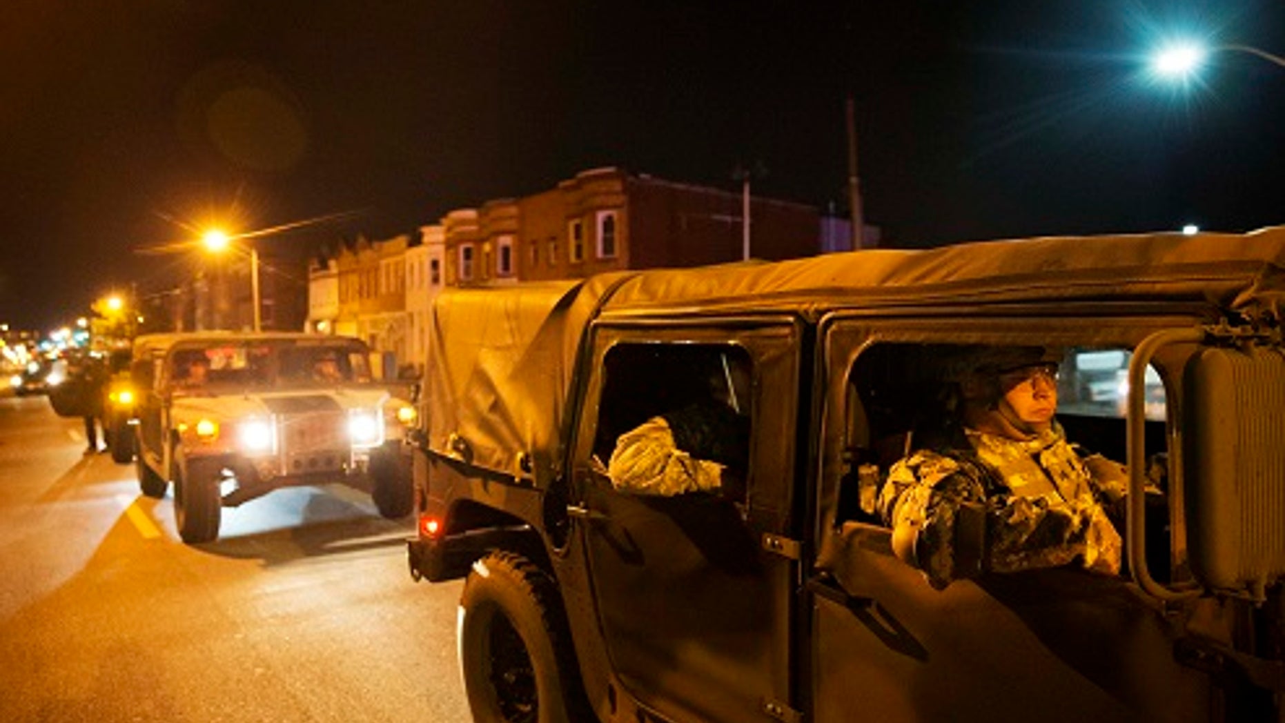 Members of the National Guard pass through the area where Monday's riots occurred following the funeral for Freddie Gray, after a 10 p.m. curfew went into effect, Tuesday, April 28, 2015, in Baltimore. (AP Photo/David Goldman)