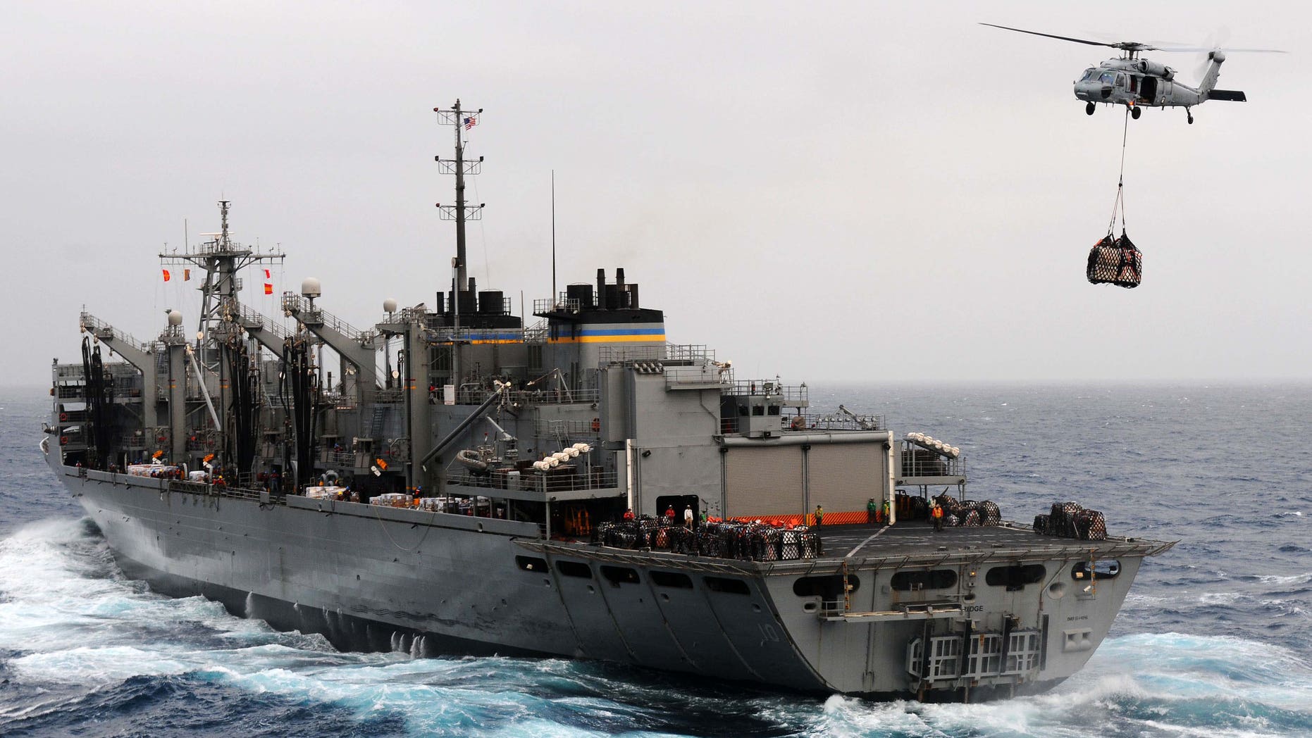 June 23, 2011: An MH-60S Sea Hawk helicopter assigned to the Wild Cards of Helicopter Sea Combat Squadron (HSC) 23 transfers cargo from the Military Sealift Command fast combat support ship USNS Bridge (T-AOE 10) during a replenishment at sea with the aircraft carrier USS Ronald Reagan (CVN 76), not pictured.