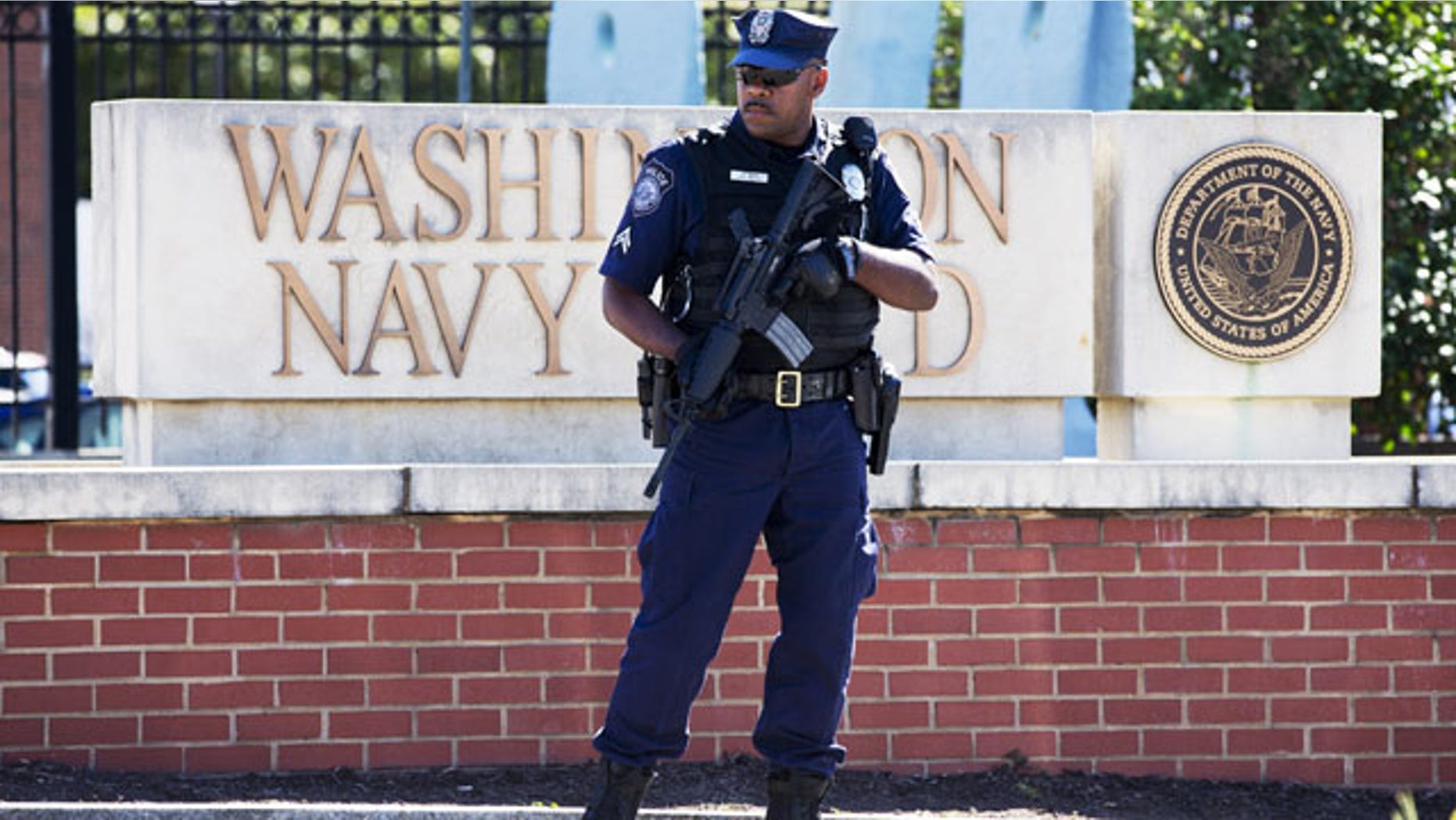 September 17, 2013: An armed officer who said he is with the Defense Department, standing near guard the gate at the Washington Navy Yard the day after a gunman launched an attack inside the Yard. An independent review triggered by the Washington Navy Yard killings last year says threats to Defense Department personnel and facilities increasingly are coming from within. It says the department must rethink its outdated security theory that suggests defending the perimeters can keep threats away. Instead, it says that terrorism, espionage and even physical threats are coming from trusted insiders. (AP Photo/Jacquelyn Martin, File)