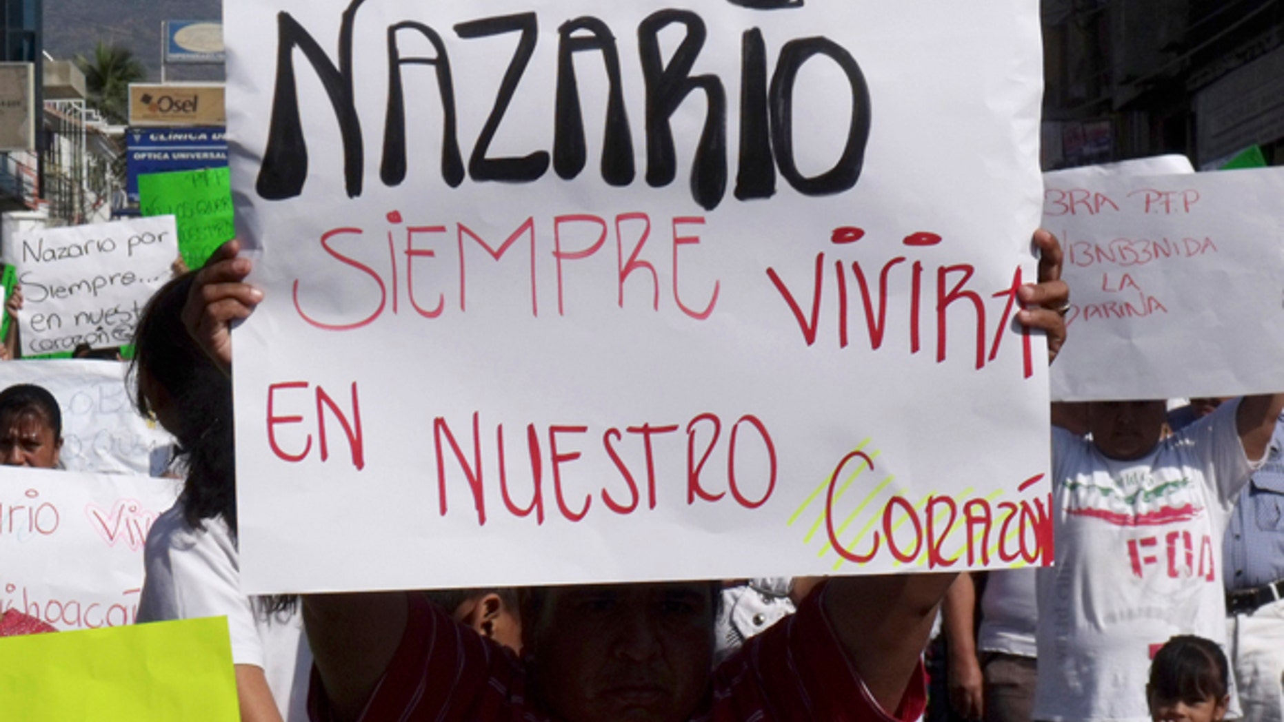 FILE - In this Dec. 12, 2010 file photo, a man holds a sign that reads in Spanish "Nazario will always live in our hearts," referring to La Familia drug cartel leader Nazario Moreno Gonzalez during a demonstration after the government announced he was killed in Apatzingan, Mexico. Years later on Sunday, March 9, 2014, officials say they are trying to determine if a man killed in an early morning shootout is Moreno. Some residents of Michoacan have reported seeing Moreno as his former cartel, La Familia Michoacana, was morphing into the more vicious and powerful Knights Templar. (AP Photo/Primera Plana, File)