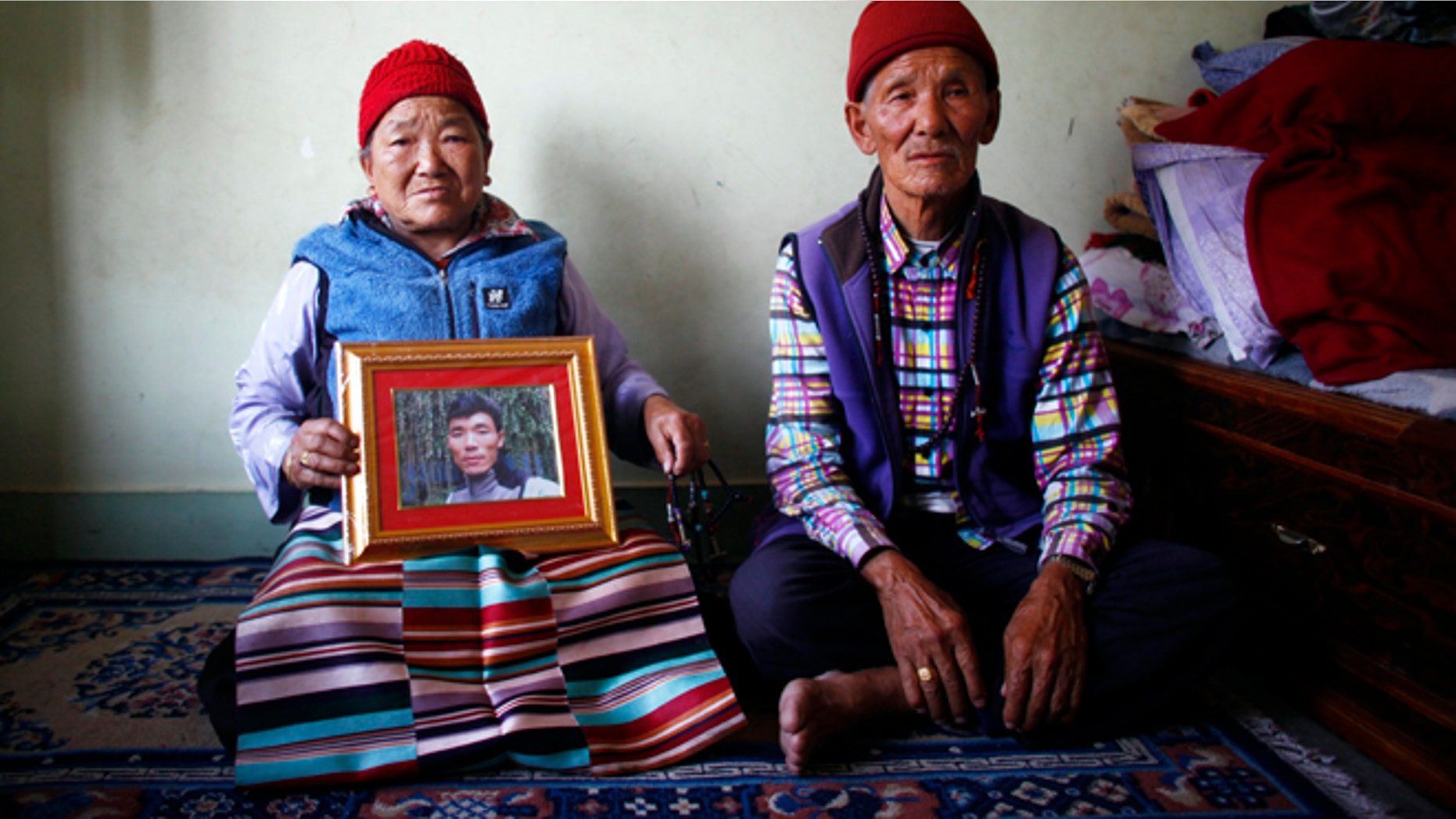April 23, 2014: Nimdige Sherpa holds a portrait of her son Ang Kaji Sherpa, killed in an avalanche on Mount Everest, with her husband Ankchu Sherpa seated beside her in their rented apartment in Katmandu, Nepal. (AP)