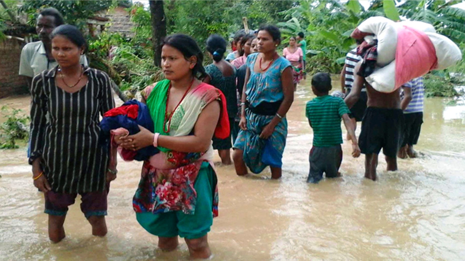 August 15, 2014: Nepalese villagers carry their belongings while wading through a flooded street to move to safer ground, at Bardia, in western Nepal. (AP Photo/Bhabuk Yogi)