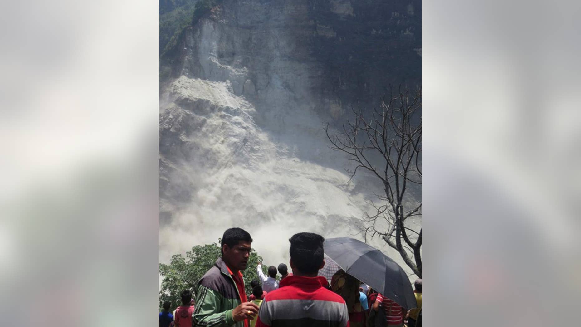 People gather at the site of a landslide north of Beni Bazaar, Nepal, Sunday, May 24, 2015. Thousands of people fled villages and towns along a mountain river in northwest Nepal on Sunday after it was blocked by a landslide that could burst and cause flash floods, officials said. (AP Photo/M.B. Astha)