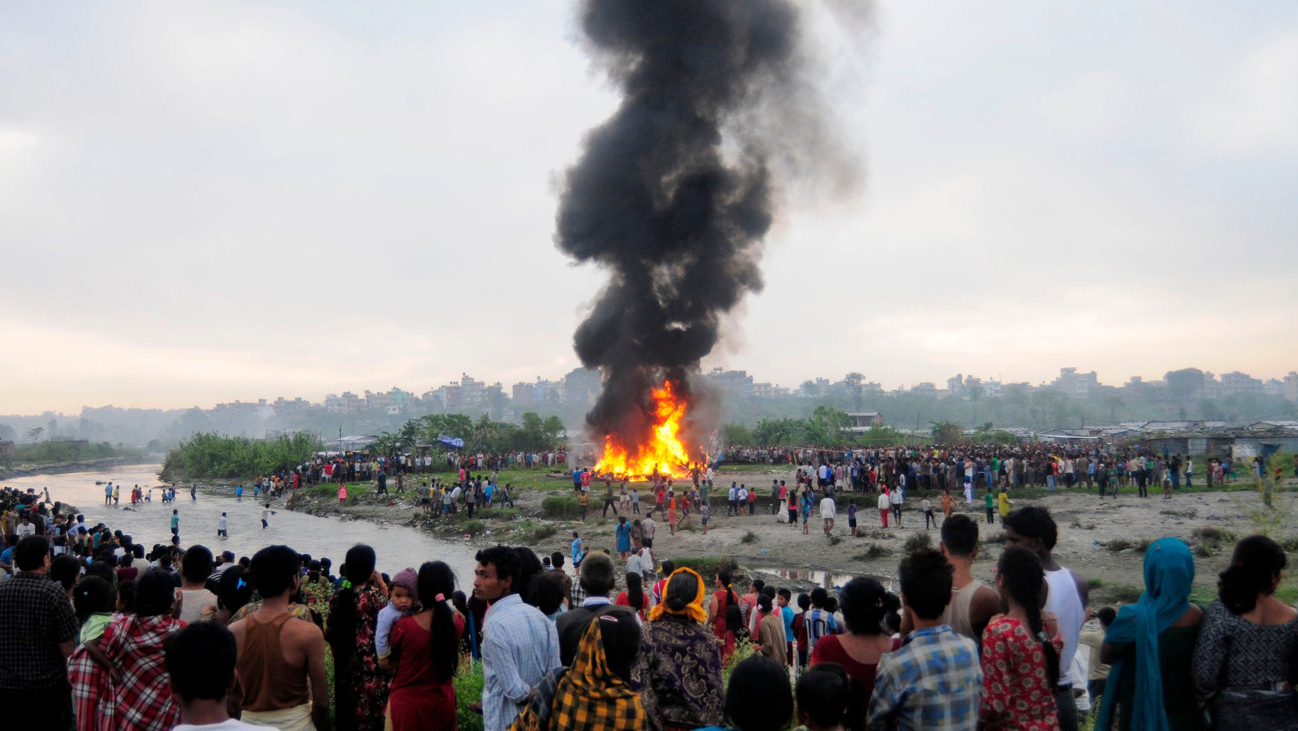 Nepalese gather around the burning wreckage at the crash site of a Sita Air airplane near Katmandu, Nepal, early Friday, Sept. 28, 2012. The plane carrying trekkers into the Everest region crashed Friday morning in Nepal's capital, and all 19 people on board are believed dead, authorities said. Thirteen people on board were foreigners, while three passengers and the three crew members were from Nepal, said Katmandu airport chief Narayan Bastakoti. (AP Photo)