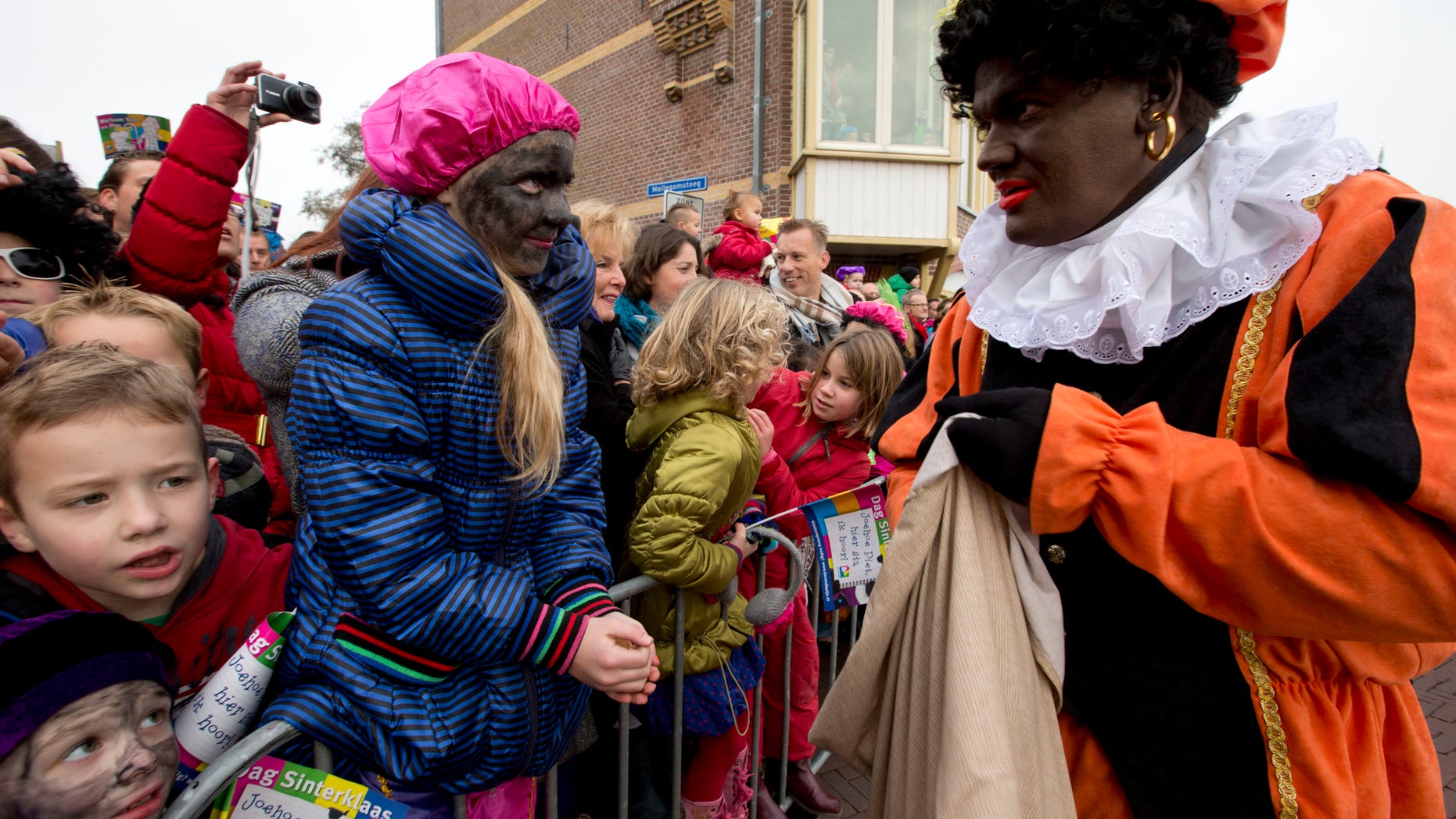 Nov. 16, 2013: Children, some with faces painted black, wait for "Zwarte Piet" or "Black Pete", right, to hand them candy after they arrived with Sinterklaas, or Saint Nicholas, in Hoorn, north-western Netherlands.