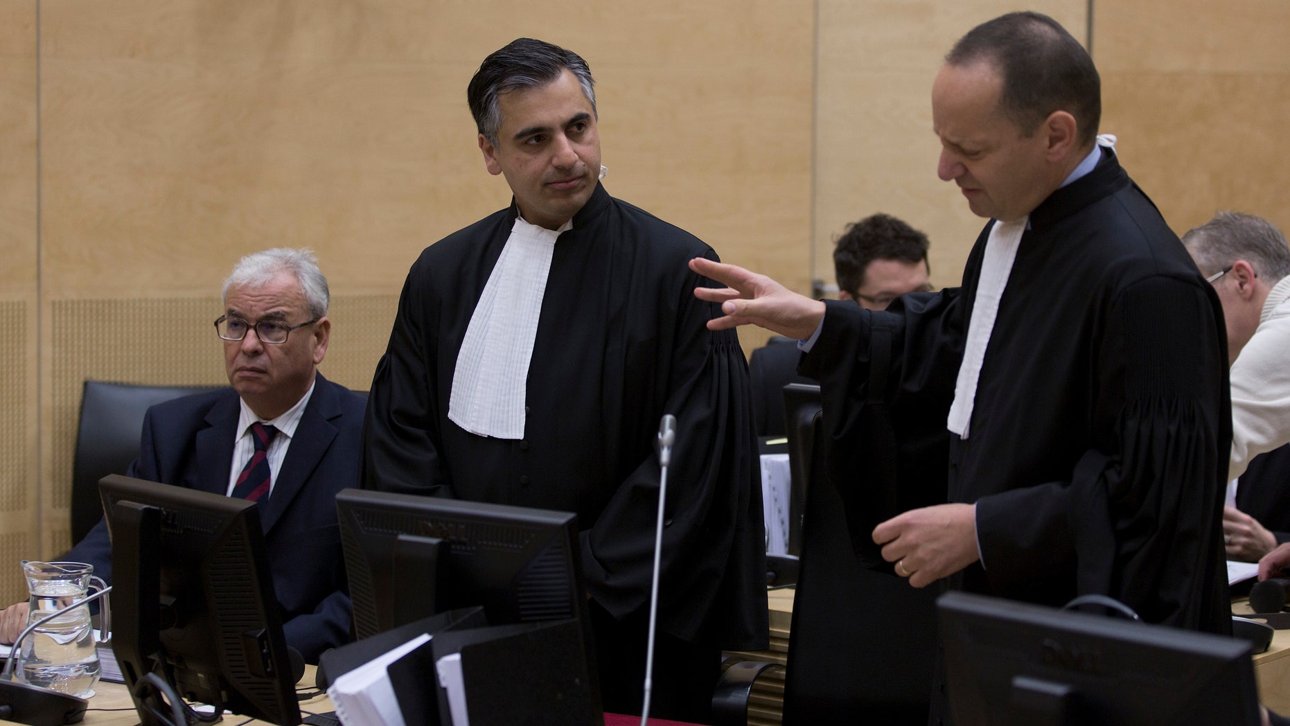 Representatives of Libya, Ahmad Sadeq Al Gehani, left, and Payam Akhavan, center, and Phillippe Sands, right, discuss at the start of a hearing of the International Criminal Court on Libya's challenge to the admissibility of the case against Seif Al-Islam Gaddafi in The Hague, Netherlands, Tuesday Oct. 9 2012. The International Criminal Court is holding a two-day hearing into where the eldest son of former Libyan dictator Moammar Gadhafi should be put on trial. Seif al-Islam Gadhafi is charged by the international court with crimes against humanity for his alleged involvement in the deadly crackdown on dissent against his father's rule. However Libyan authorities say they want to prosecute him at home, where he is being held. (AP Photo/Michael Kooren, POOL)