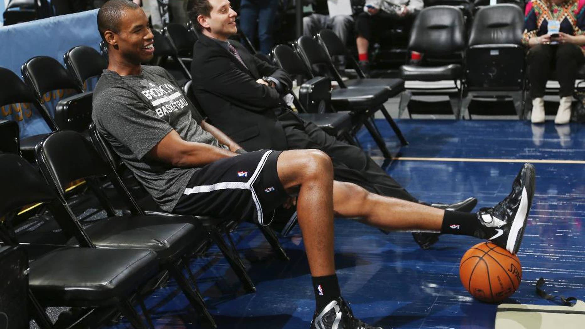 Brooklyn Nets center Jason Collins sits in a courtside seat after warming up for the Nets' NBA basketball game against the Denver Nuggets in Denver on Thursday, Feb. 27, 2014. (AP Photo/David Zalubowski)