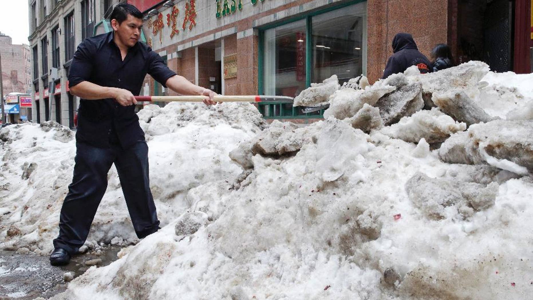 FILE - In this March 4, 2015 file photo, waiter Melvin Angel shovels snow outside the restaurant he works at in the Chinatown neighborhood of Boston. Every work day lost during New England’s historic winter has meant millions of dollars out of the regional economy. Retailers and restaurants were among the hardest hit, but hotels, transportation companies and other tourism businesses struggled too. (AP Photo/Charles Krupa)