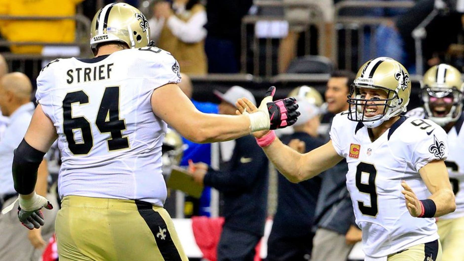 Oct 4, 2015; New Orleans, LA, USA; New Orleans Saints quarterback Drew Brees (9) and tackle Zach Strief (64) celebrates following an 80 yard game winning touchdown pass during overtime against the Dallas Cowboys at the Mercedes-Benz Superdome. The Saints won 26-20. The touchdown pass by Brees was the 400th touchdown pass of his career. Mandatory Credit: Derick E. Hingle-USA TODAY Sports