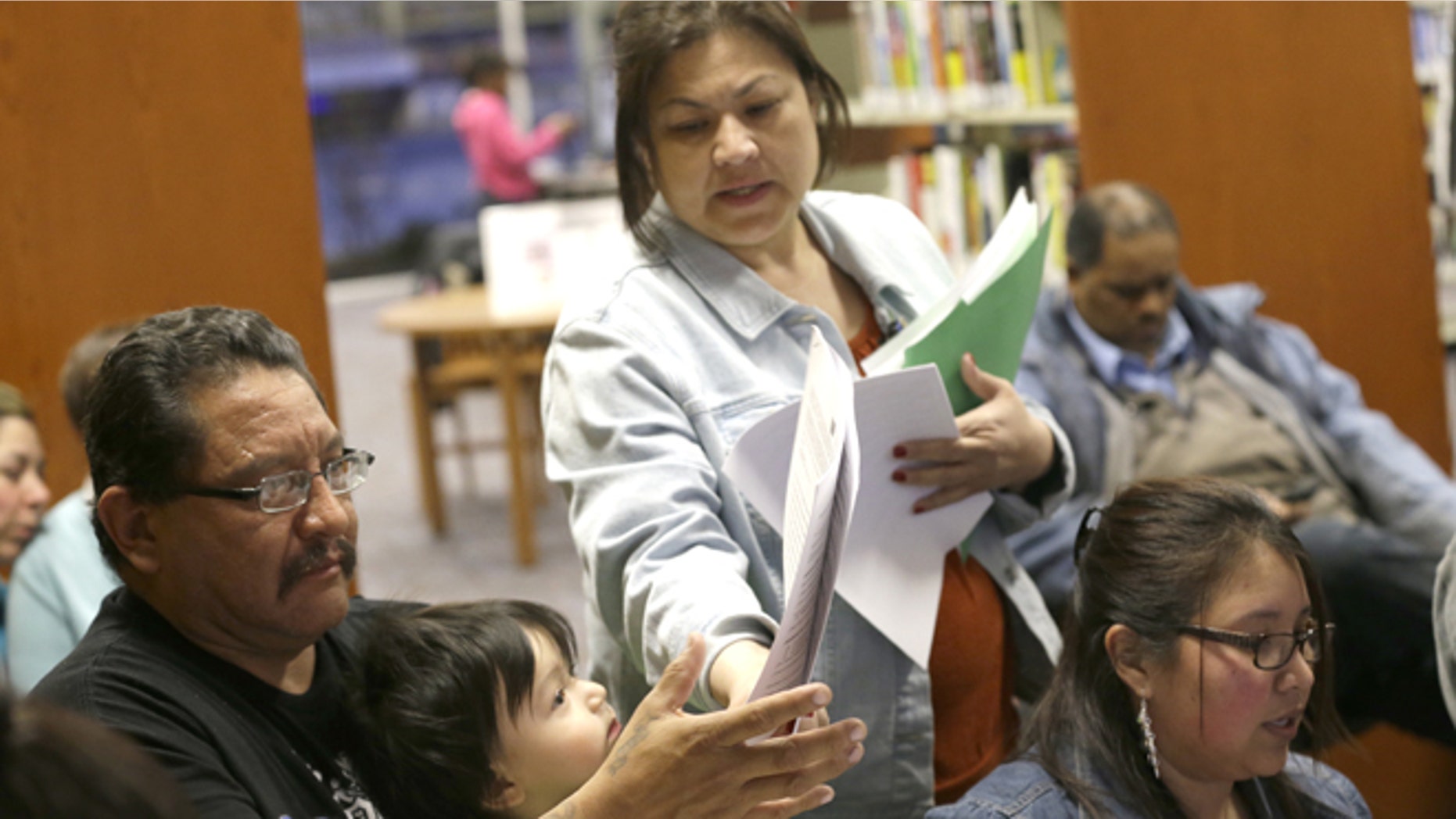 In this photo made Thursday, Feb. 12, 2015, JPS Health Network patient navigator Delaila Hernandez, center, helps Fred Cardenas with documents during a Affordable Care Act enrollment event at the Fort Worth Public Library in Fort Worth, Texas. Enrollment drives are being held across the country to help people beat the deadline to sign up for health insurance through the federal marketplace. But in Texas and more than two dozen other states where millions of people fall into a so-called coverage gap, the outreach effort has involved more than just signups. (AP Photo/LM Otero)