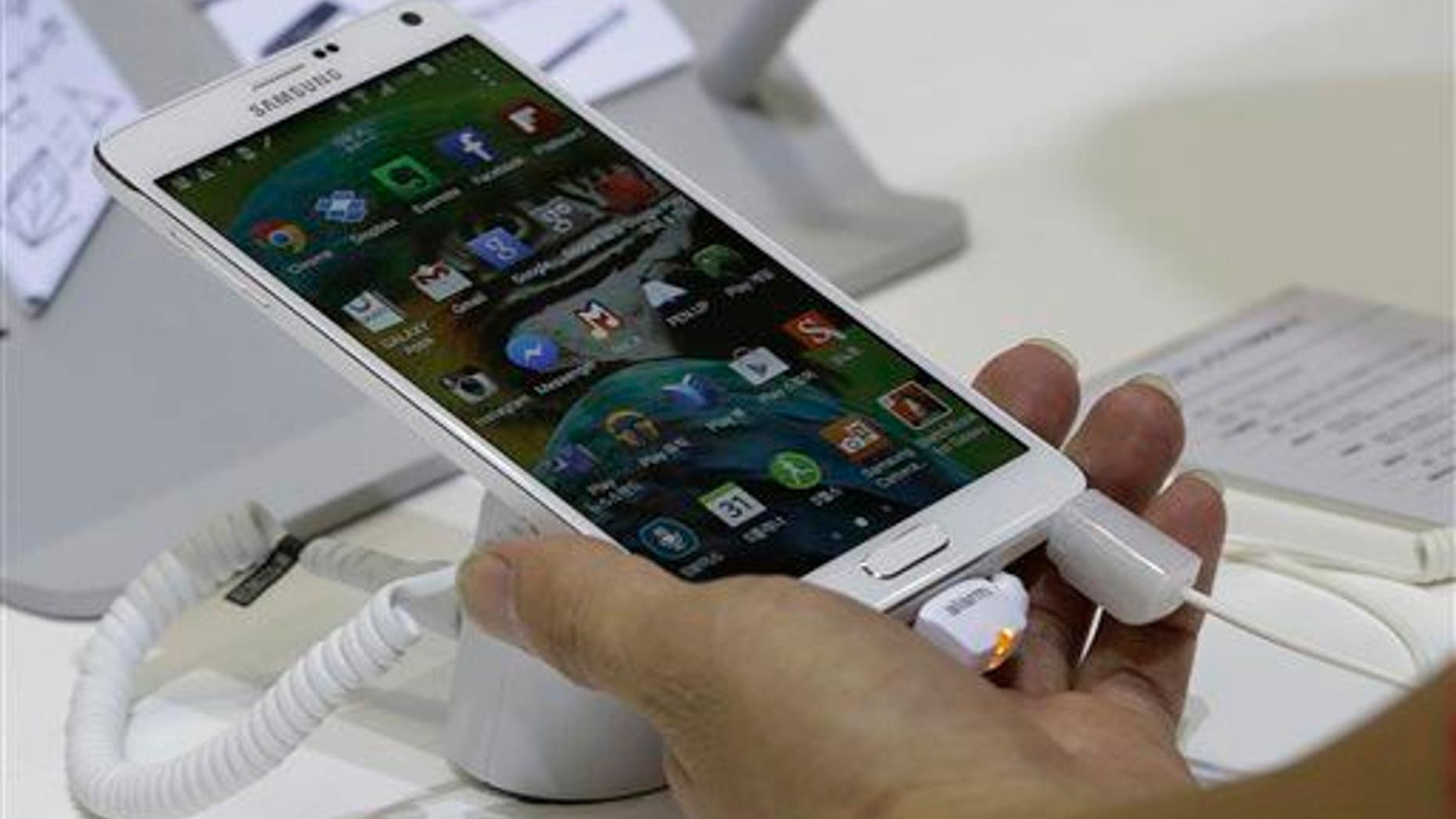 A visitor tries out a Samsung Electronics Co.'s Galaxy Note 4 smartphone during the 2014 Korea Electronics Show in Goyang, South Korea, Tuesday, Oct. 14, 2014.