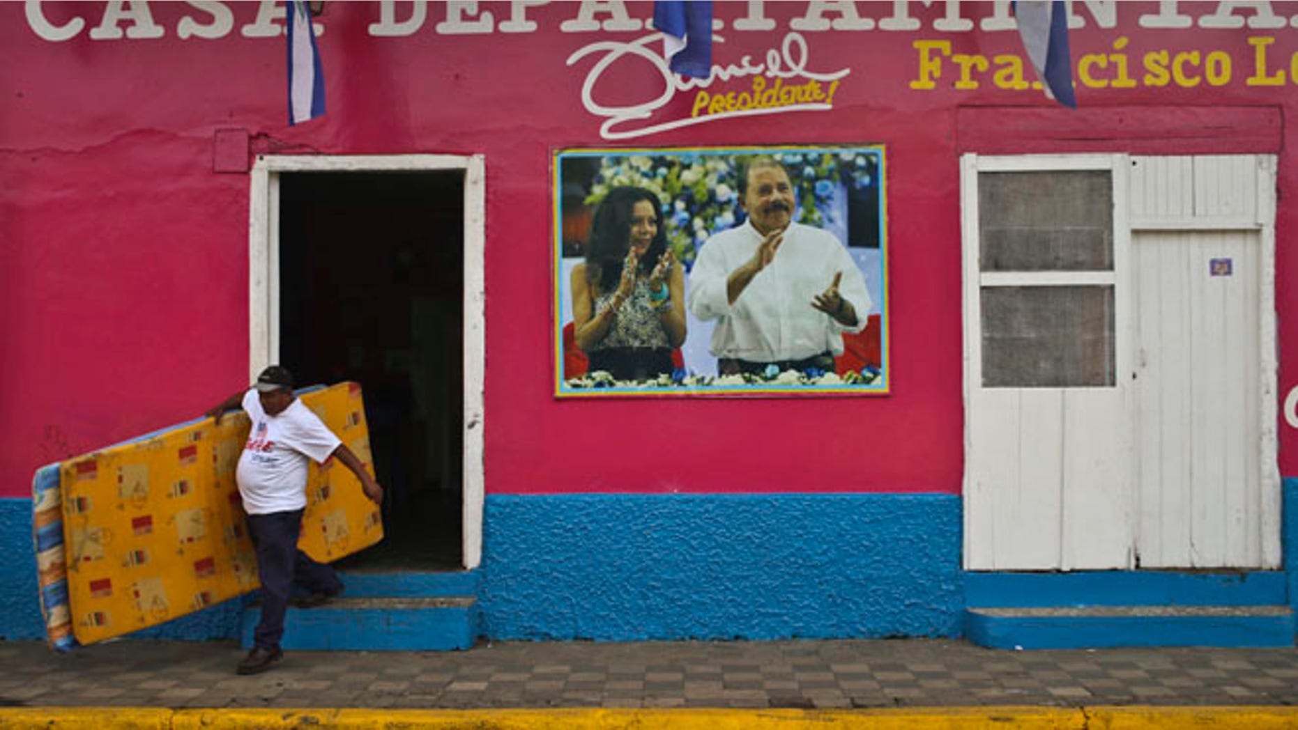 A man leaves the Sandinista National Front Party headquarters, in Masaya, Nicaragua, Saturday, Nov. 5, 2016. Nicaraguan President Daniel Ortega, pictured on the facade of the headquarters with his running mate and wife, Rosario Murillo, appears to have a clear path to a third consecutive term following recent moves that weakened the countryââ¬â¢s opposition. (AP Photo/Esteban Felix)