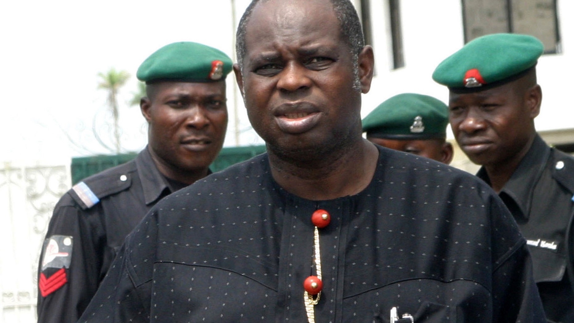 FILE - Bayelsa State Governor Diepreye Alamieyeseigha, centre, stands outside his house guarded by policemen in Yenagoa, Nigeria, in this file photo dated Sunday, Nov. 27, 2005. Presidential adviser Doyin Okupe said Wednesday March 13, 2013, that Nigeria's Council of States headed by President Goodluck Jonathan has pardoned the former political benefactor of the nation's president, who was convicted of stealing millions of dollars while serving as a state governor. The decision to pardon Alamieyeseigha was greeted with derision by activists who highlight Nigeria as having one of the world's most corrupt governments. (AP Photo, File)